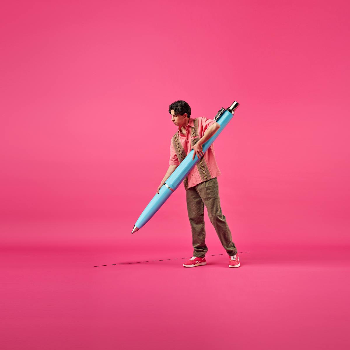 Man med stor penna, rosa bakgrund.