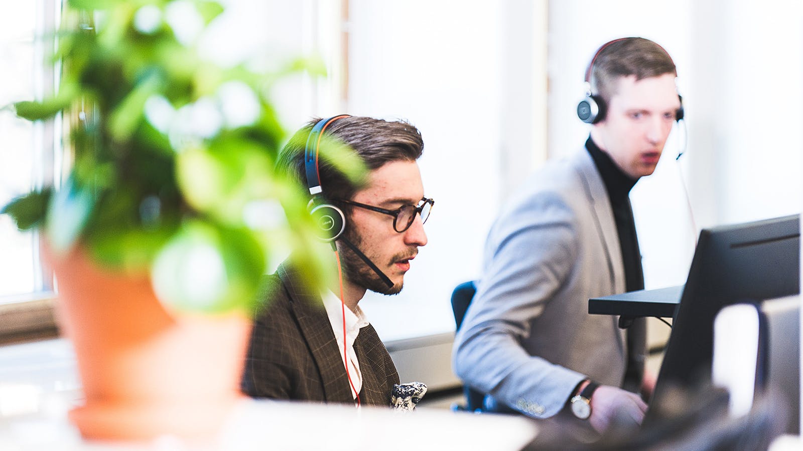 Två personer med headset och vid datorer.