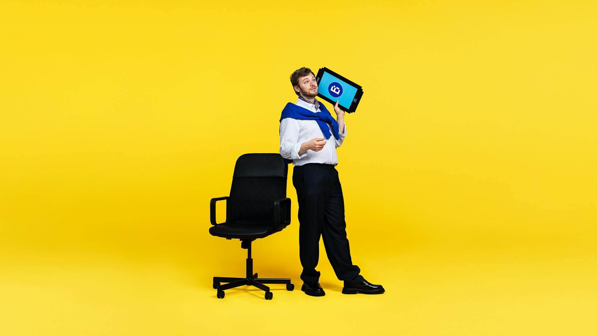 Person som står bredvid en svart kontorsstol. Pratar i en jättestor mobiltelefon.