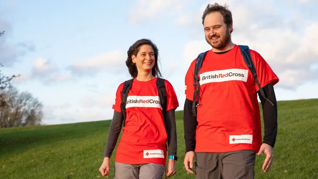 Two people in Red Cross t-shirts walking.