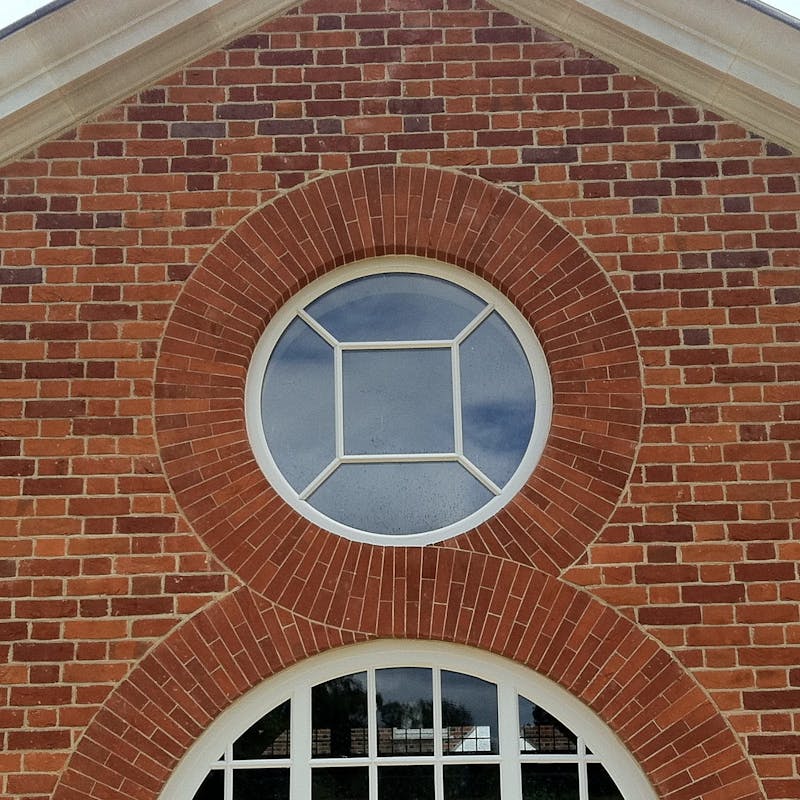Gabel end of a red brick house featuring brick window arches in a figure of eight design