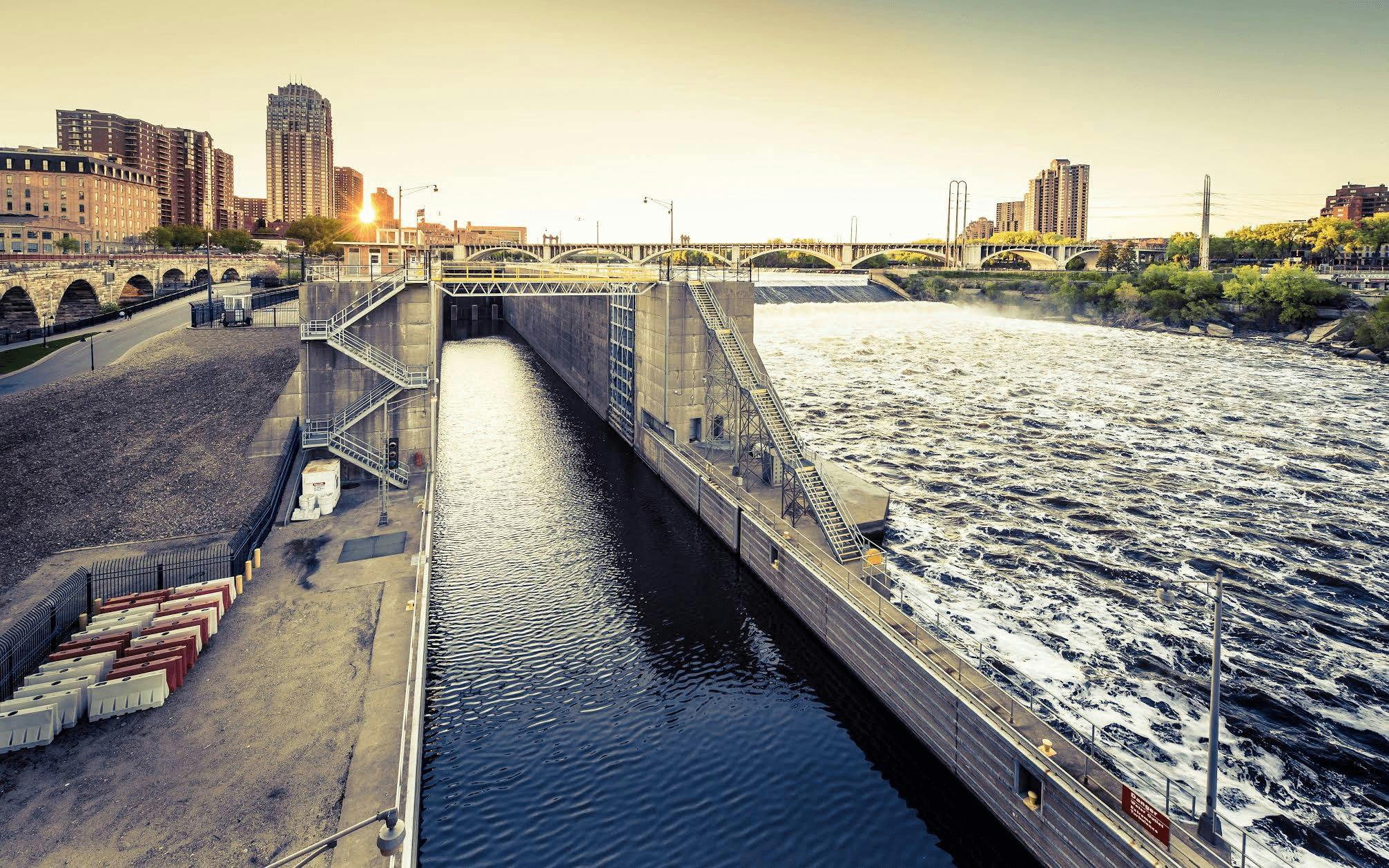 A bridge over both calm and unstable water with the city as the backdrop.