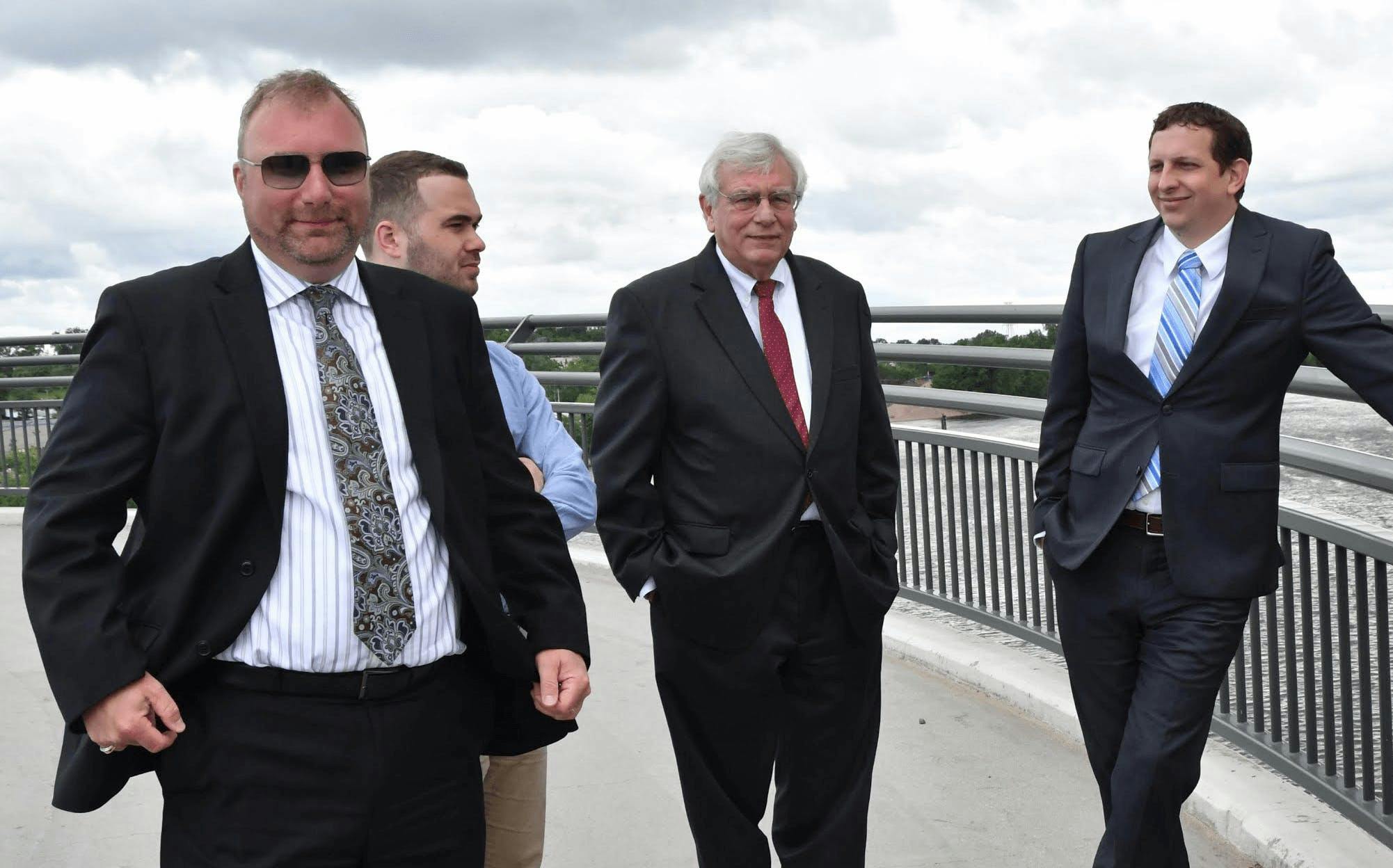 Lawyers standing on bridge with city as their backdrop.