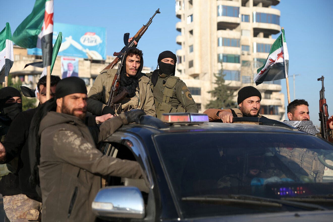 Anti-government fighters brandish their guns as they ride a vehicle in Syria's northern city of Aleppo. (Photo Credit: Omar Haj Kadour/AFP via Getty Images/JNS)