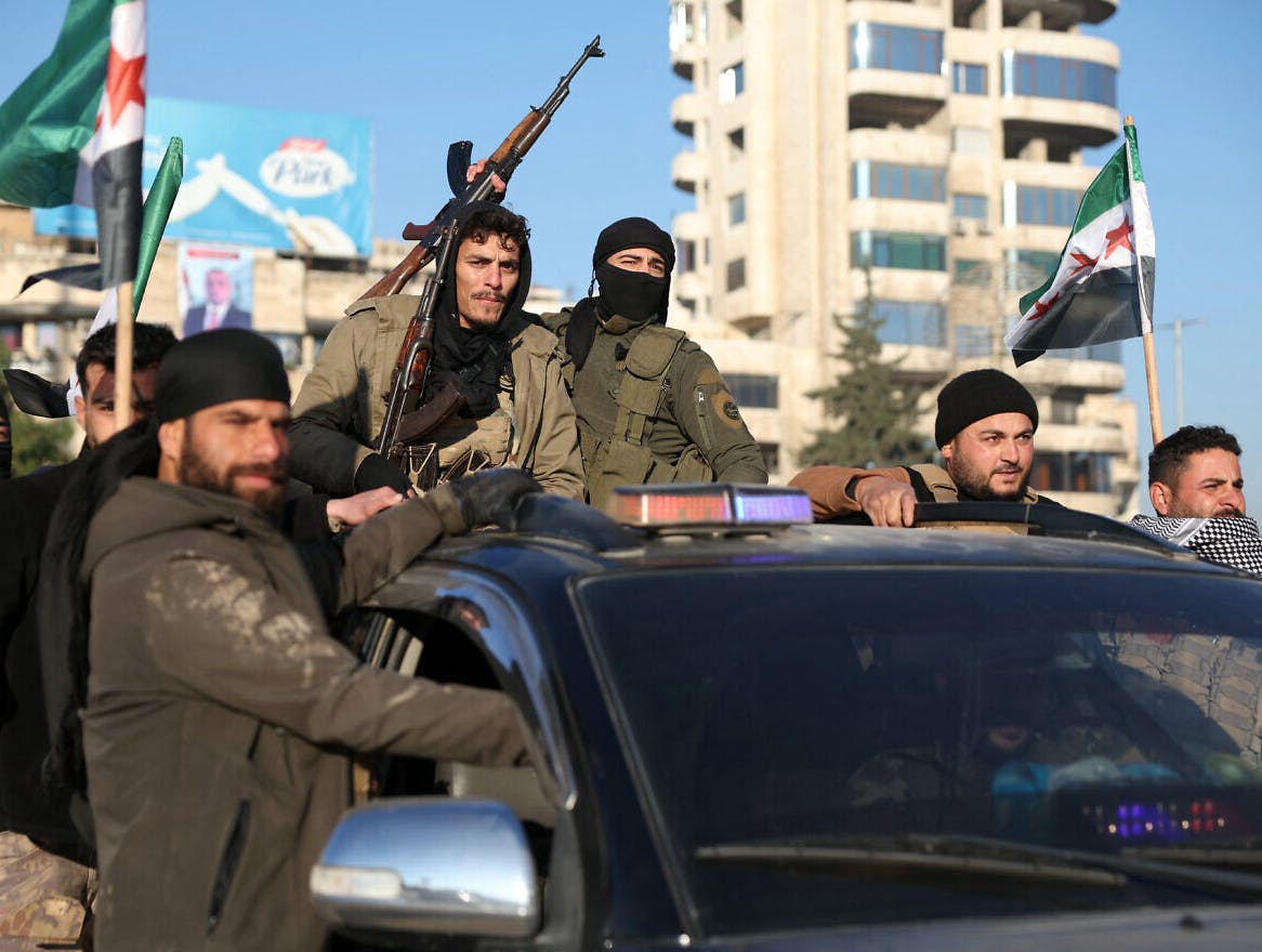Anti-government fighters brandish their guns as they ride a vehicle in Syria's northern city of Aleppo. (Photo Credit: Omar Haj Kadour/AFP via Getty Images/JNS)