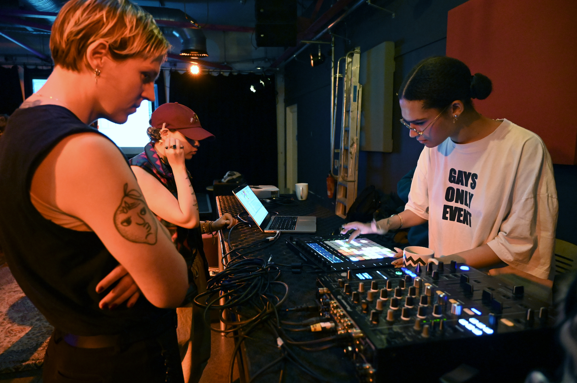 Guest artist TAAHLIAH playing a beat machine with residency artists looking and listening.