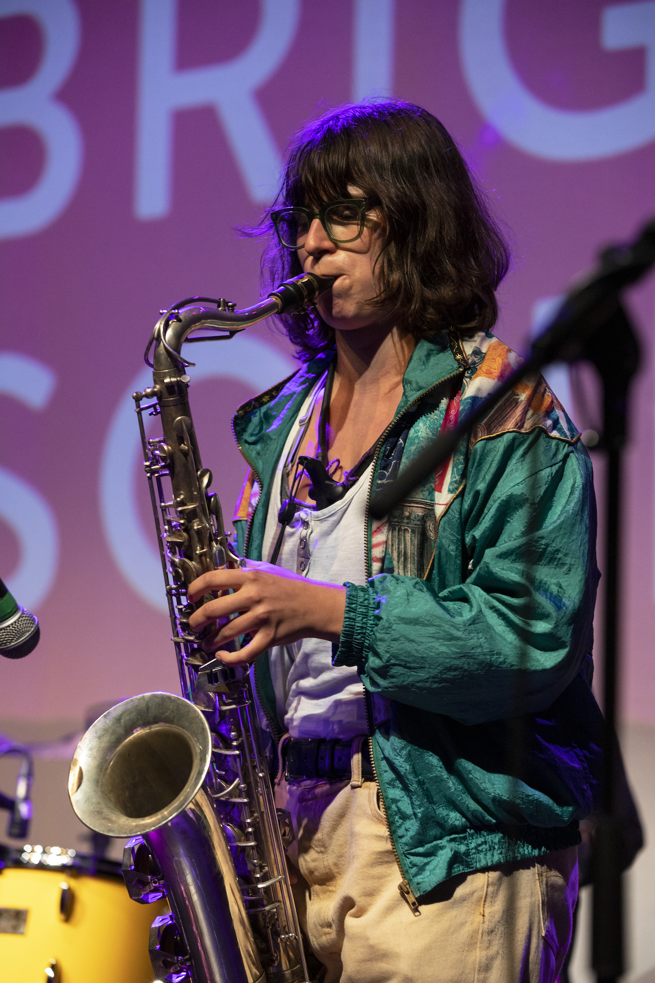 A saxophonist playing on stage dressed in a vintage green coat.
