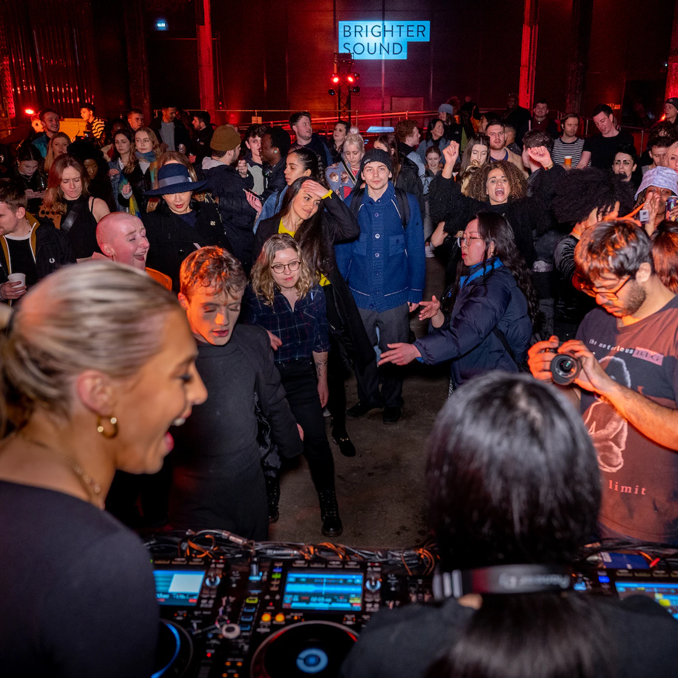 A crowd of people dancing and watching DJ collective Girls Don't Sync.