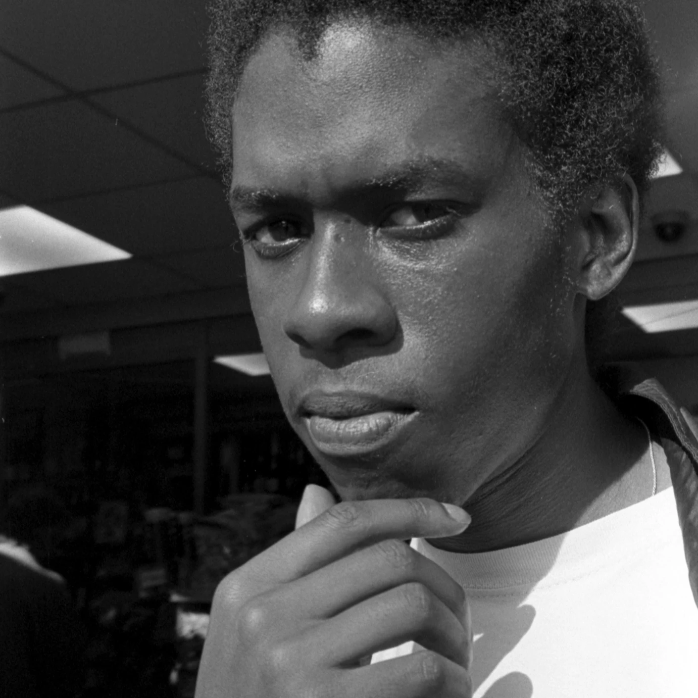 A close-up black and white image of Isaiah Hull looking directly into the camera with his hand touching his chin.