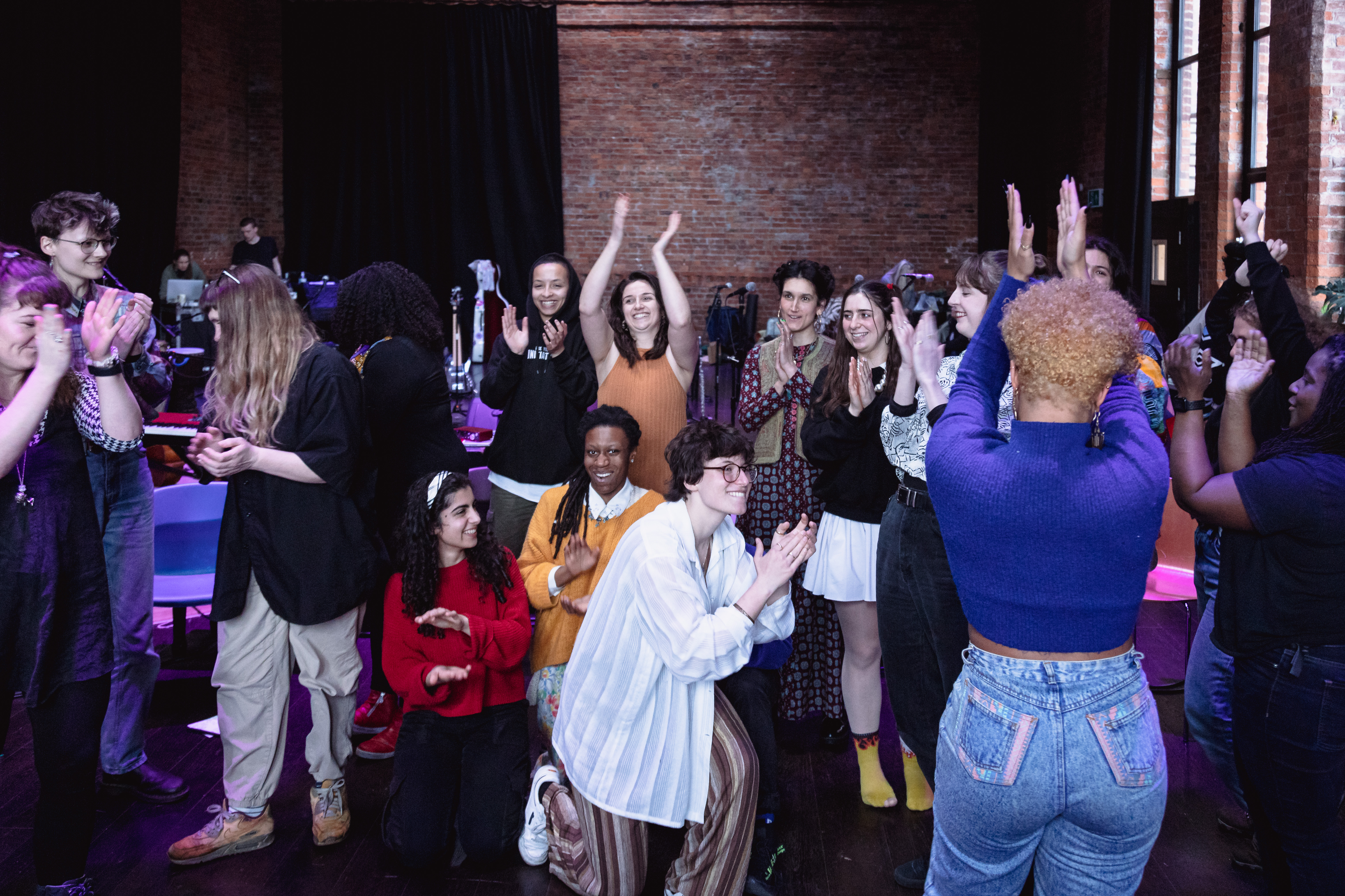Nubya Garcia and the residency participants smiling and applauding one another in a group.