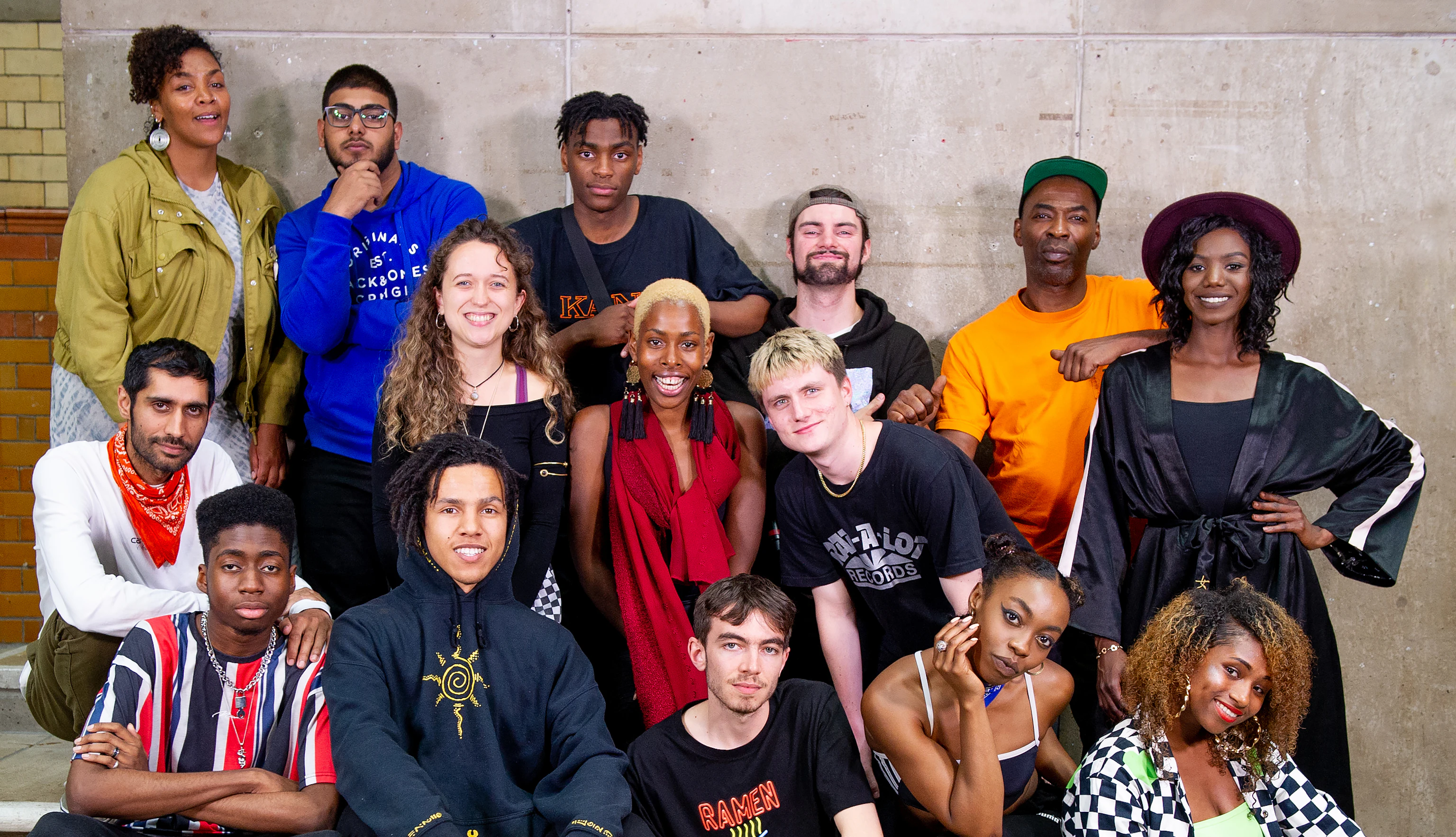 The artistic team from DISRUPT posing for the camera. Those on the left are sat or stood on a couple of small steps. Those on the right are crouched or stood. Smiles or pouts all round.