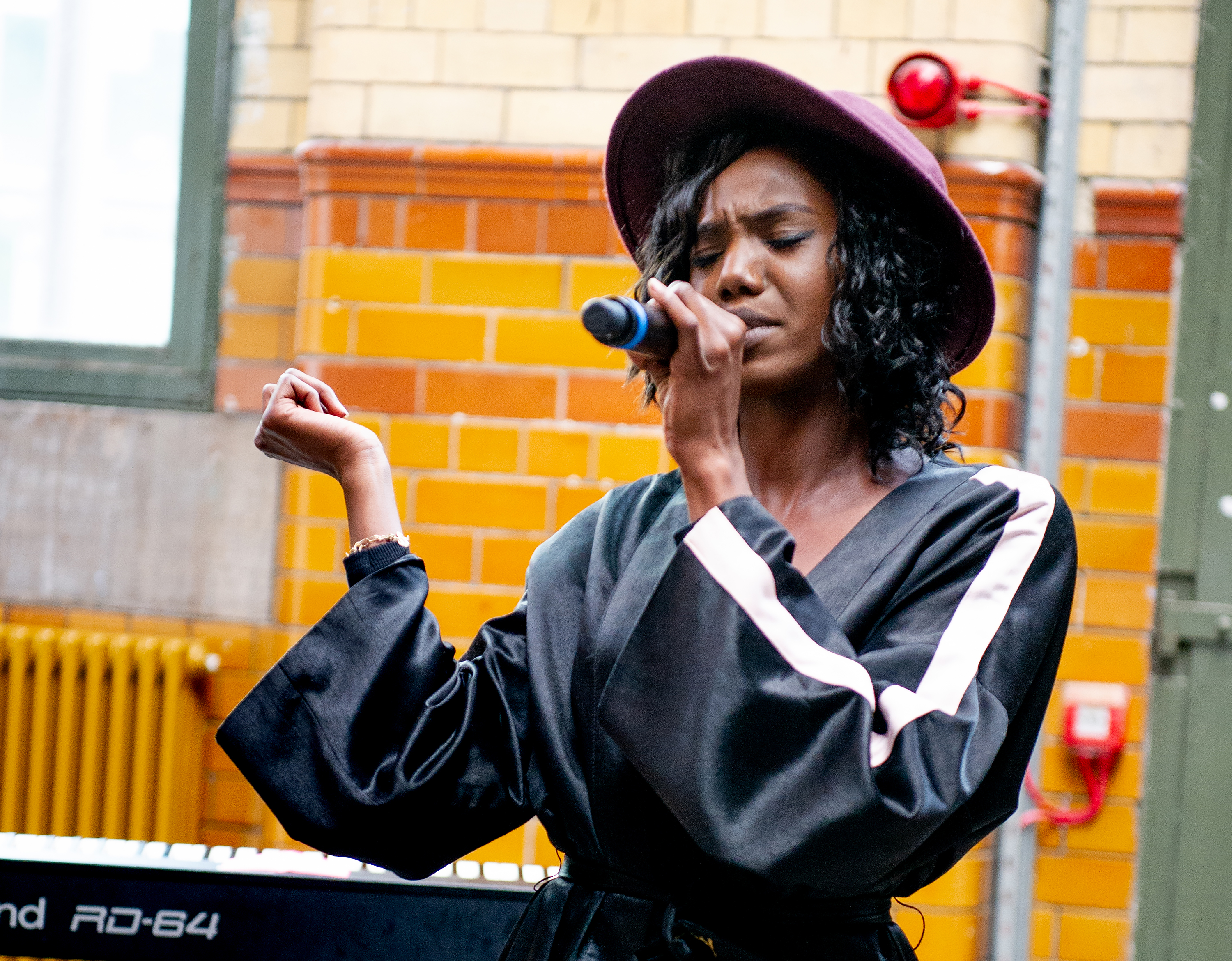 Queen Tamika singing into a microphone with her eyes shut.