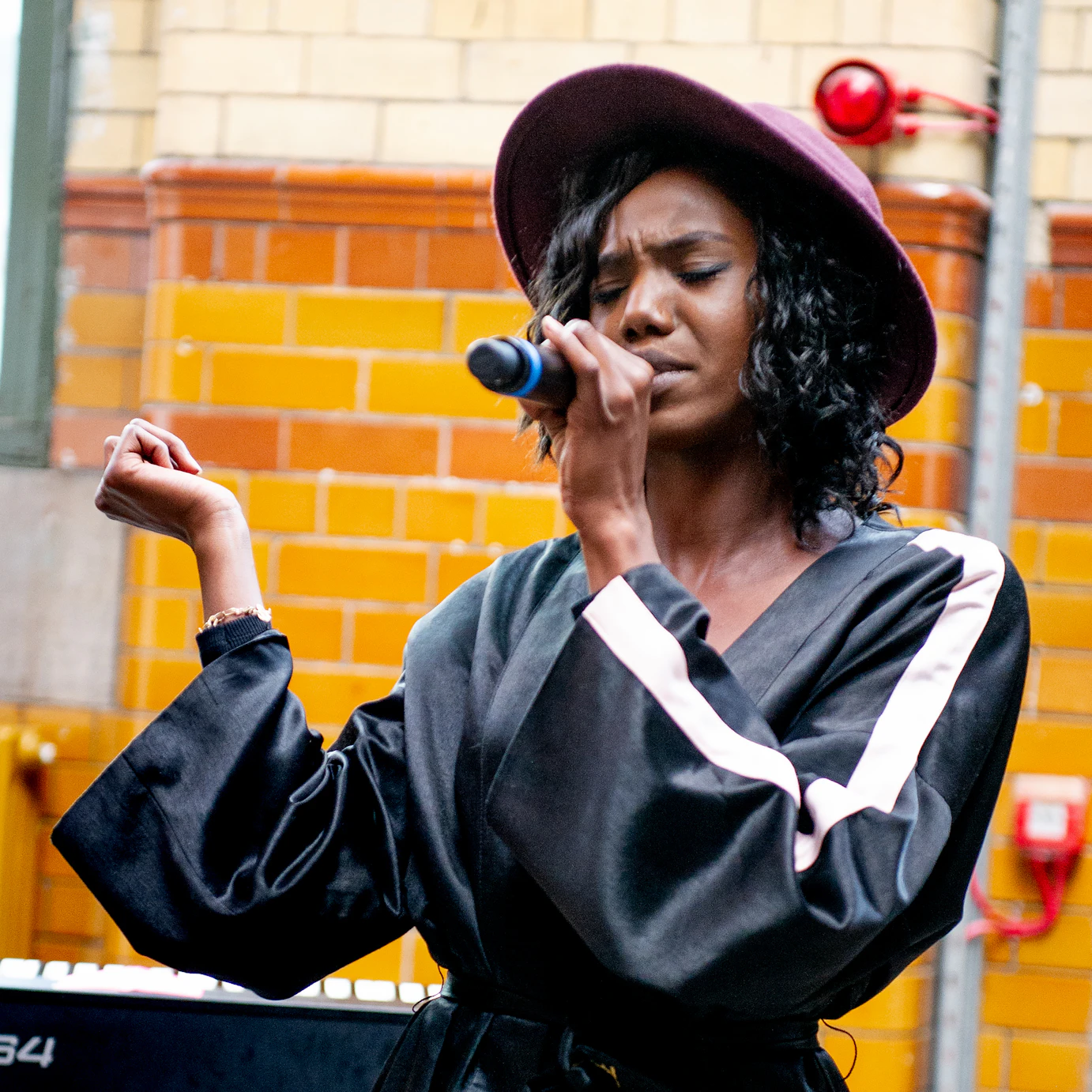Queen Tamika singing into a microphone with her eyes shut.