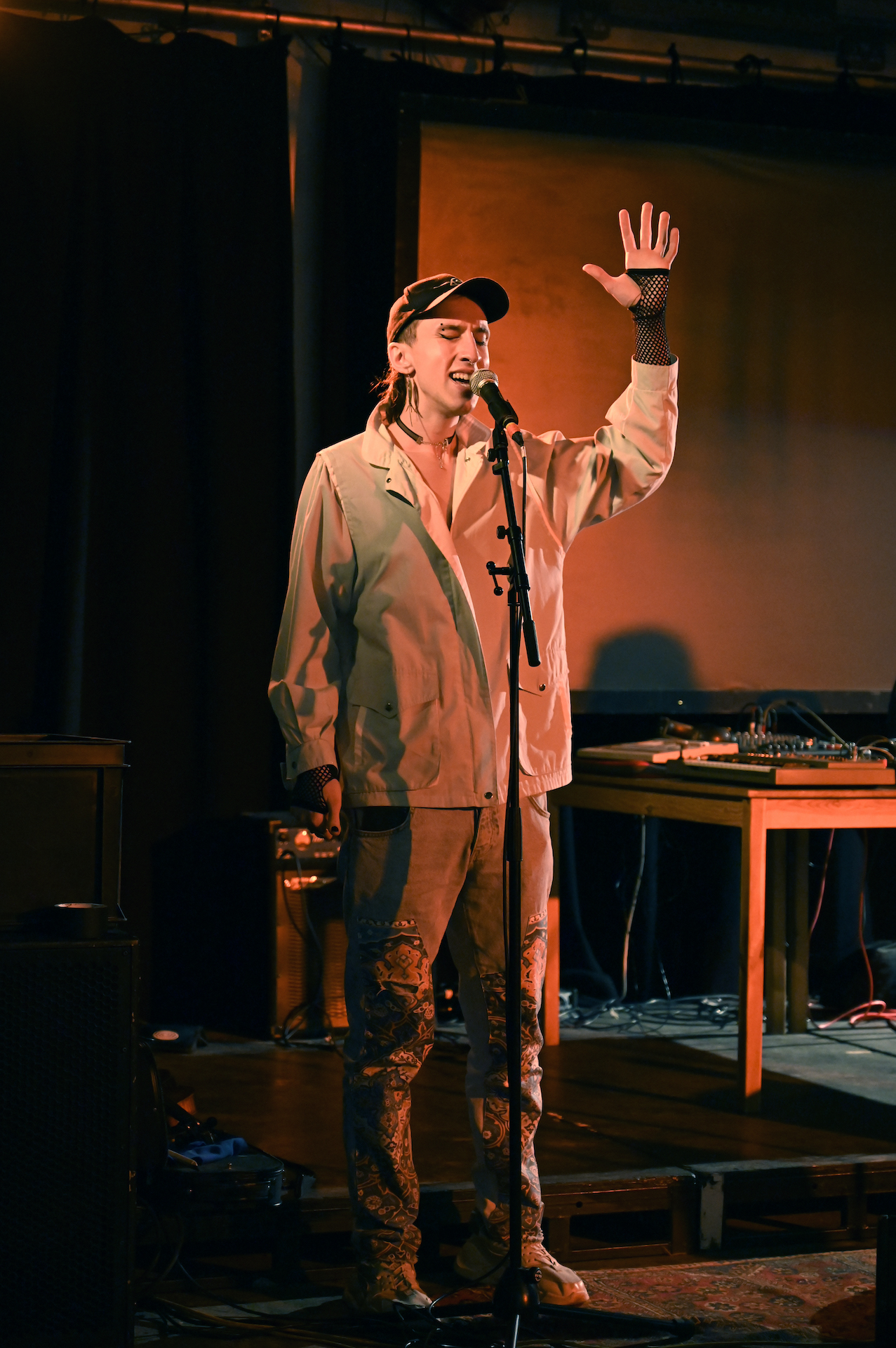 A residency artist singing into a mic with their hand in the air.