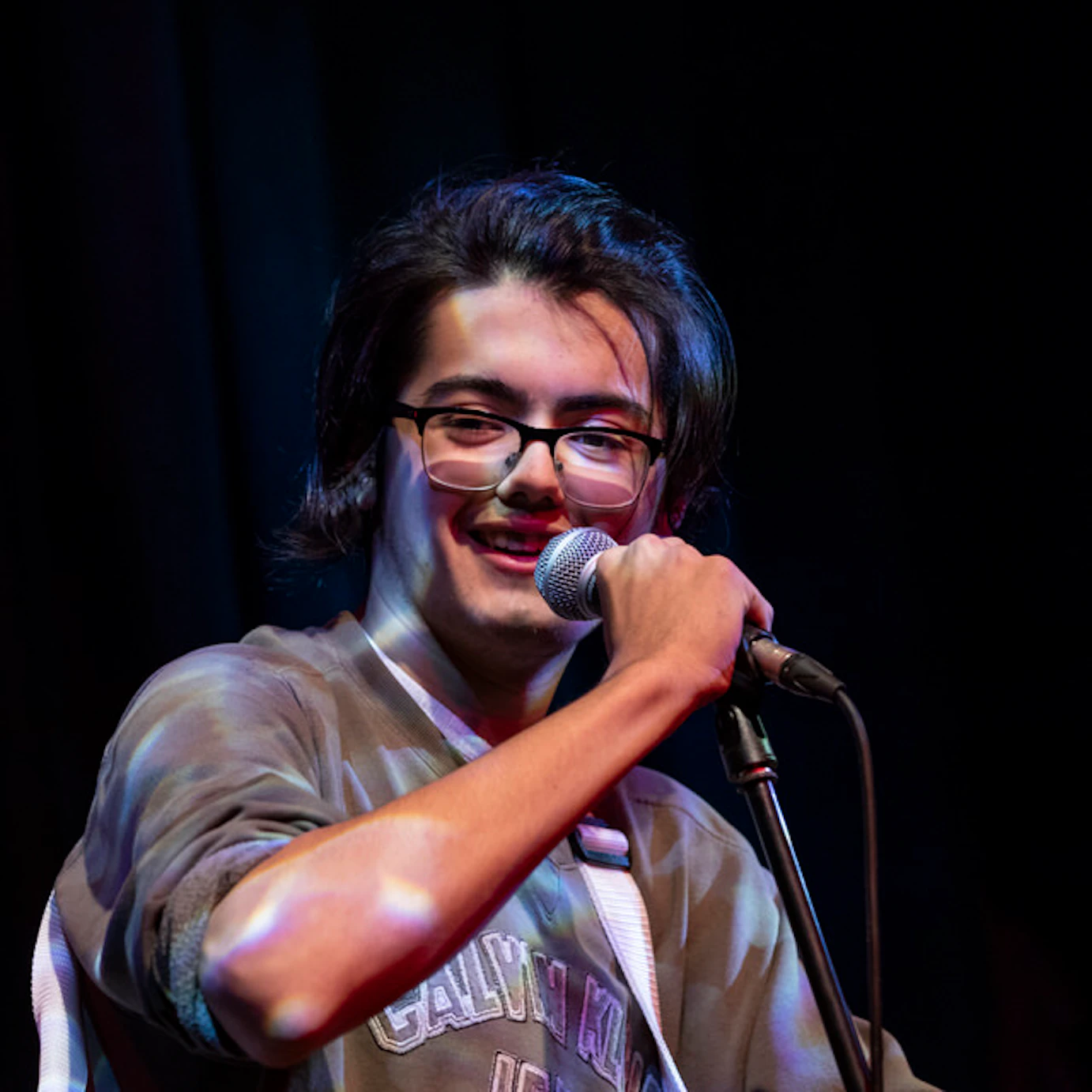 Sing City participant, Tom holds a microphone and smiles.