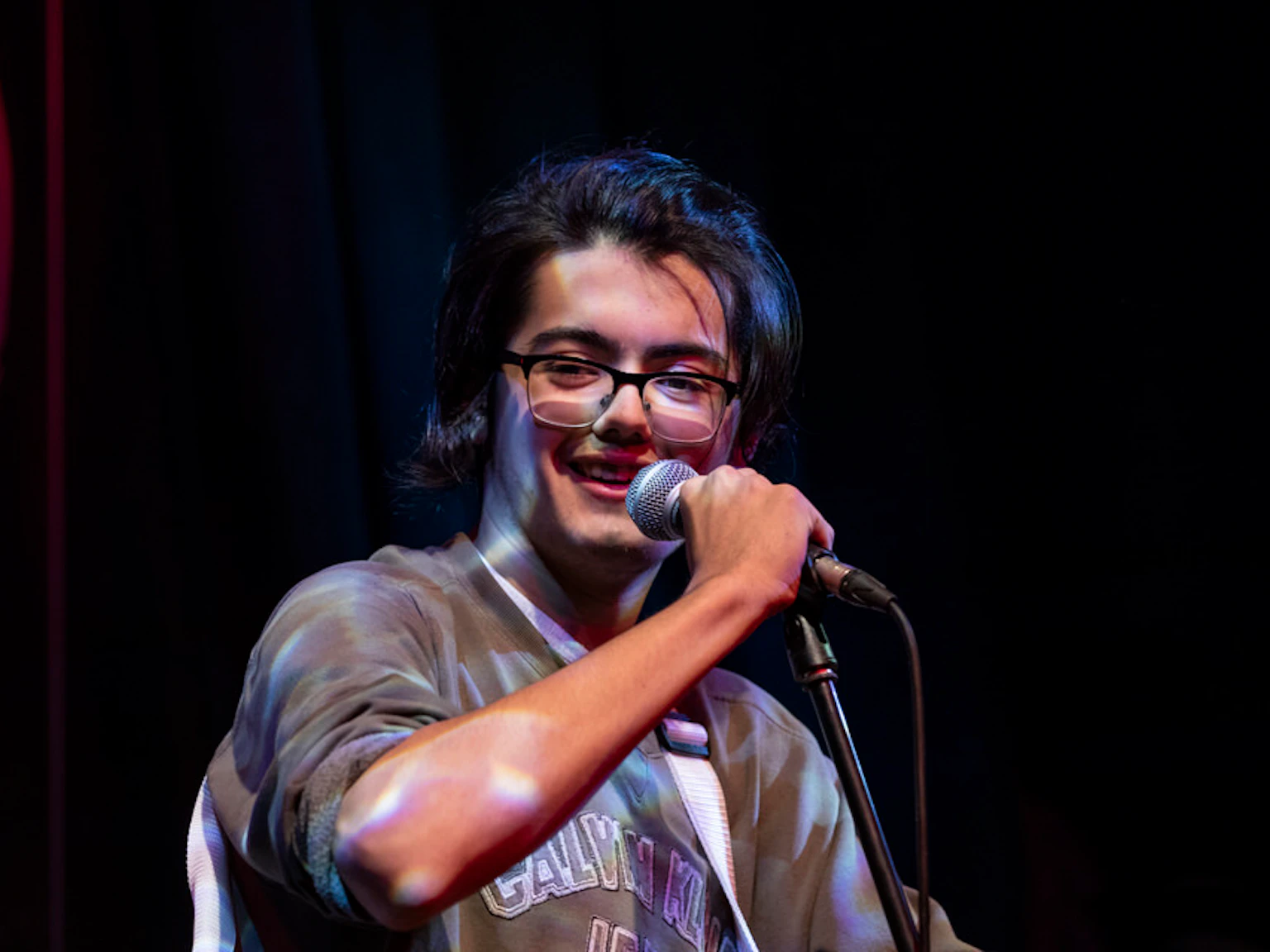 Sing City participant, Tom holds a microphone and smiles.