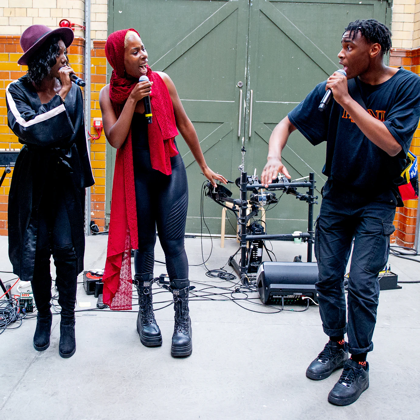 Four of the DISRUPT creative team stood in a line singing into microphones and looking at one another.
