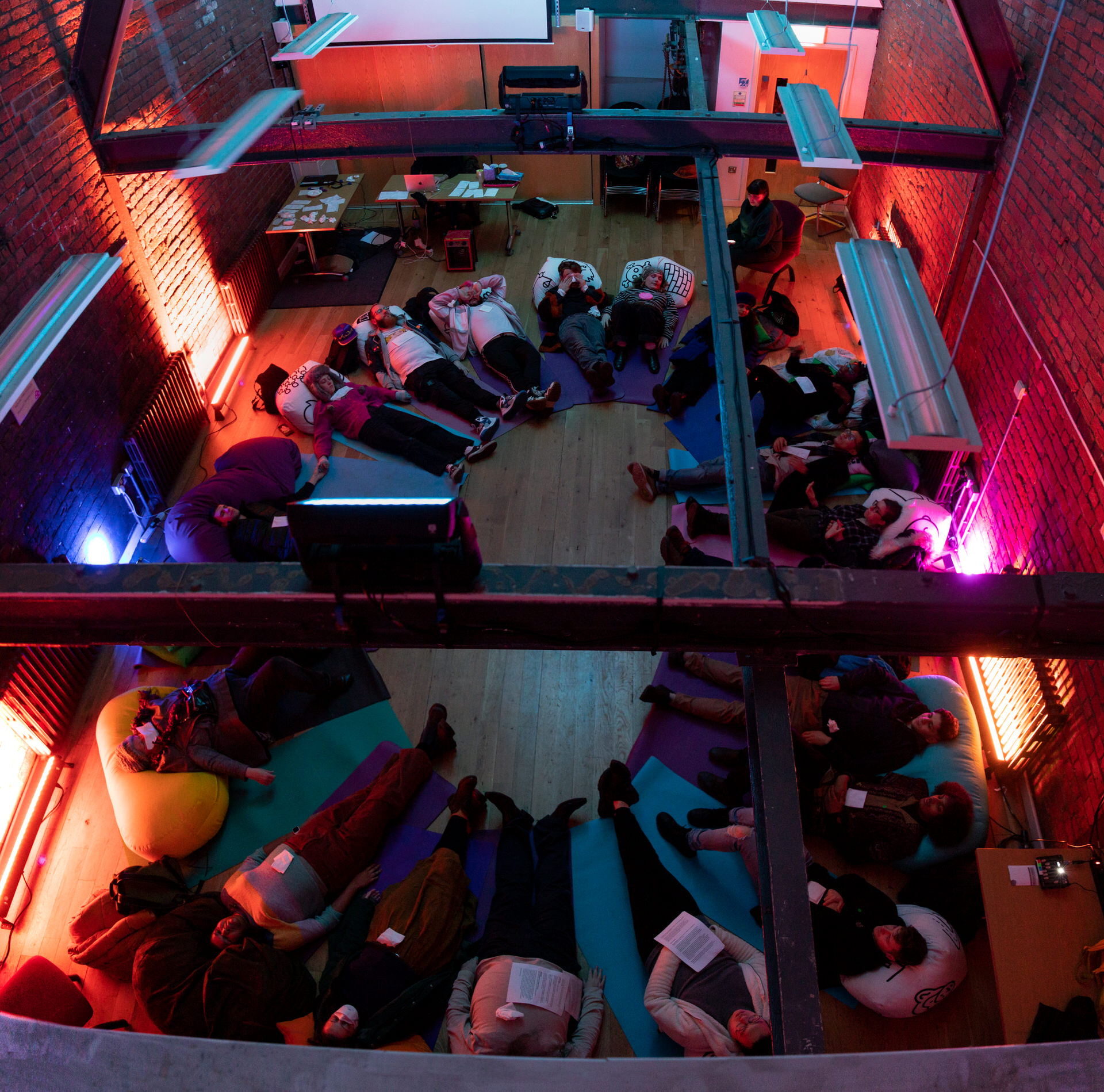 Audience members lay on cushions and yoga mats in a circle as part of the Self, Sense, Space installation.