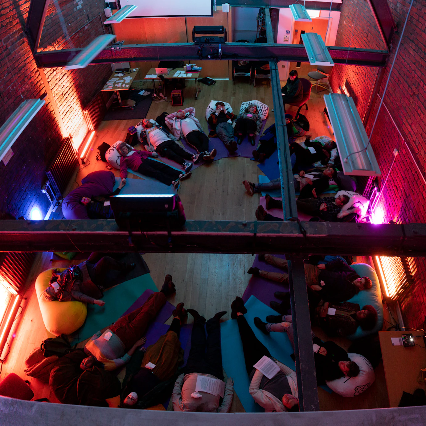Audience members lay on cushions and yoga mats in a circle as part of the Self, Sense, Space installation.