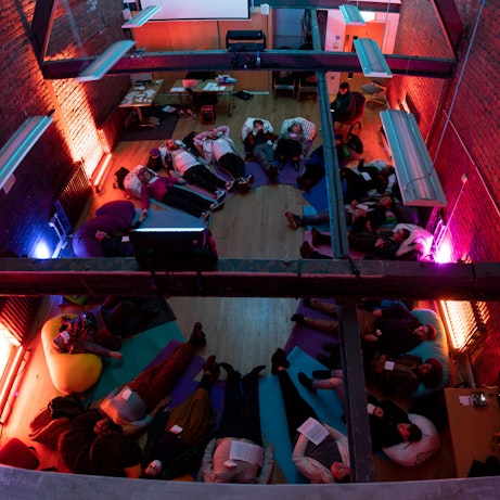 Audience members lay on cushions and yoga mats in a circle as part of the Self, Sense, Space installation.