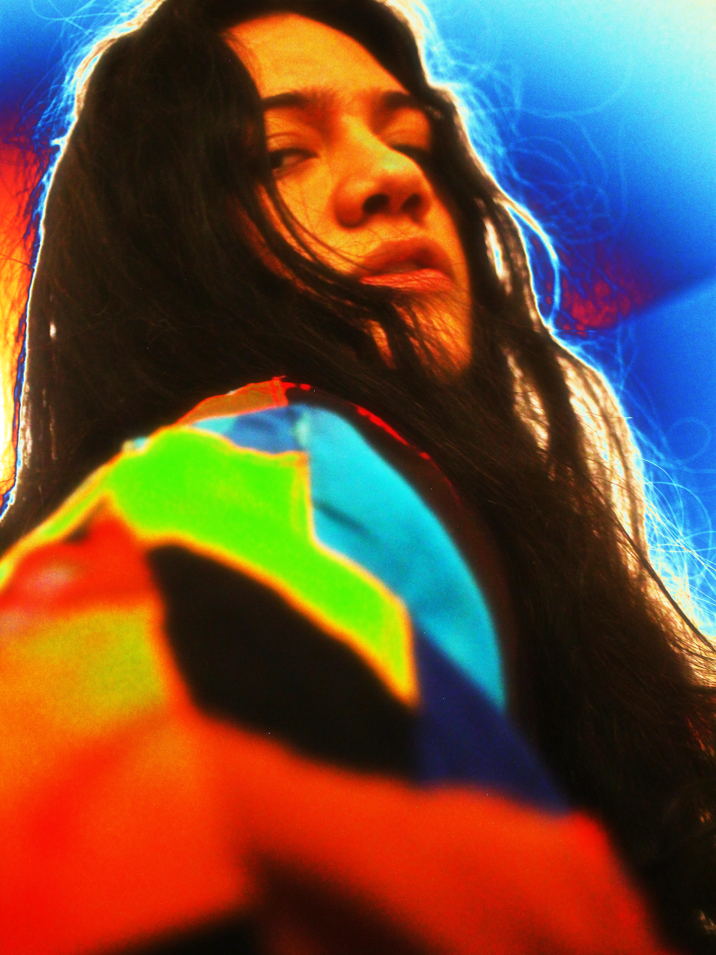 A close up of Yeguachita looking into the camera. The headshot has a heatkap style tint to it, adding reds, greens and blues to the photo.
