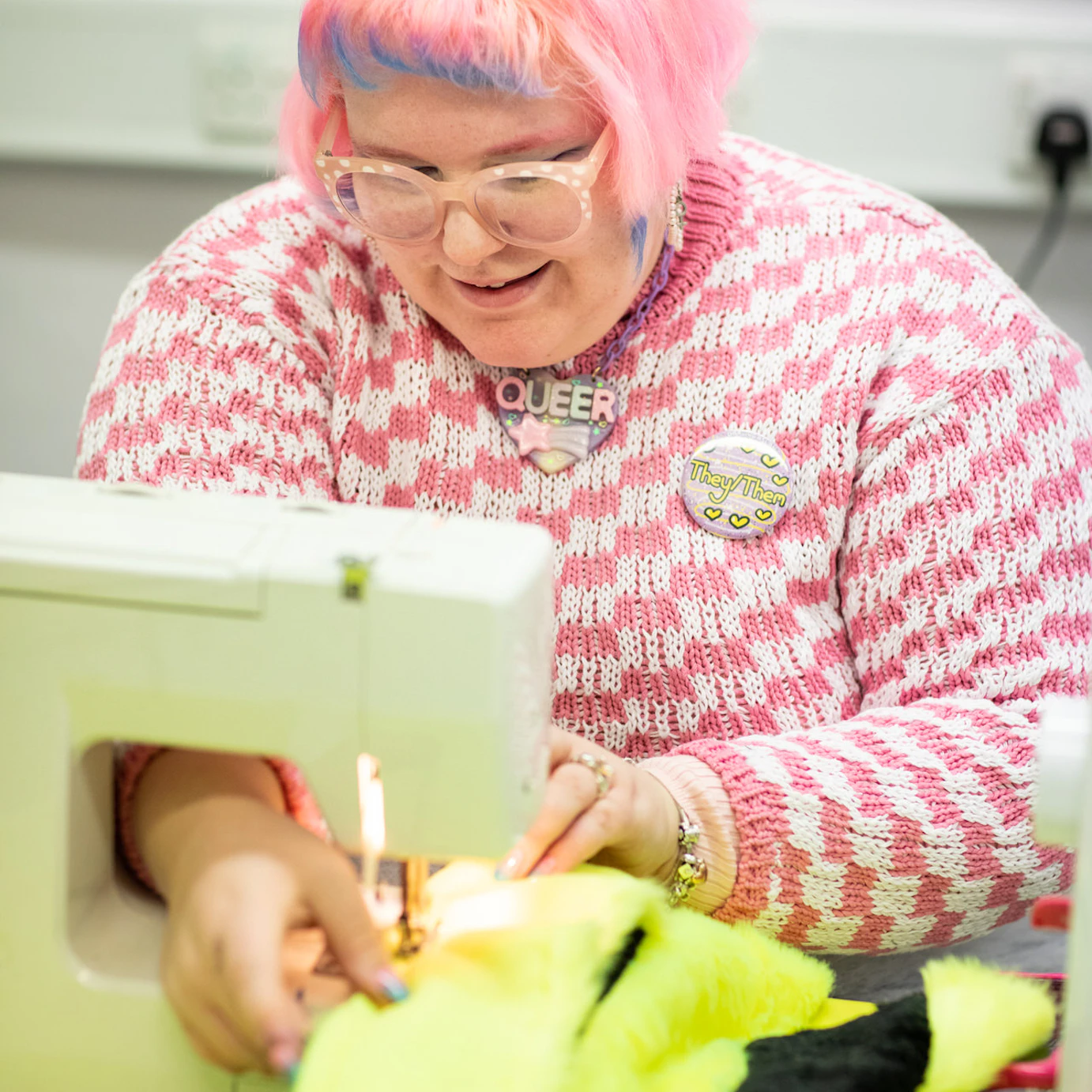 Eleanor Louise West using a sewing machine on bright green material as part of the Self, Sense, Space residency.