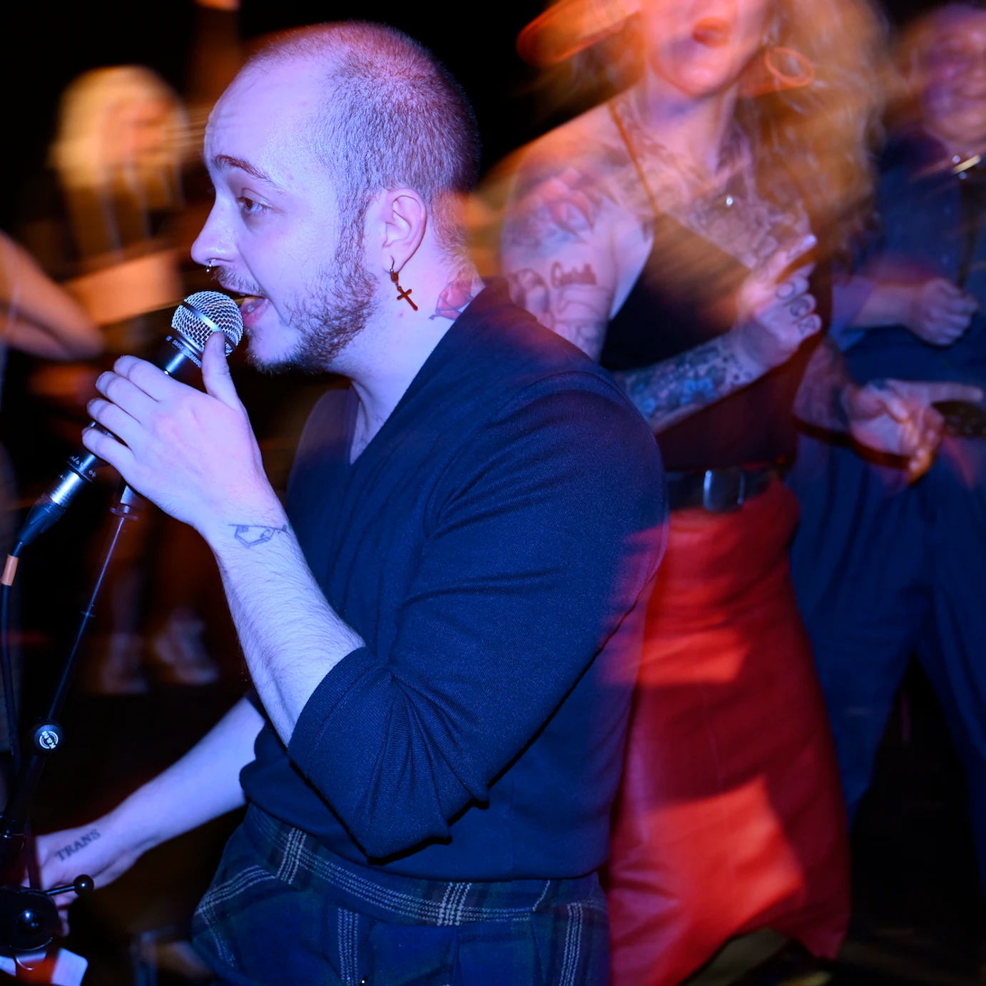 A residency artist with a mic to their lips. Around them the crowd is blurred.