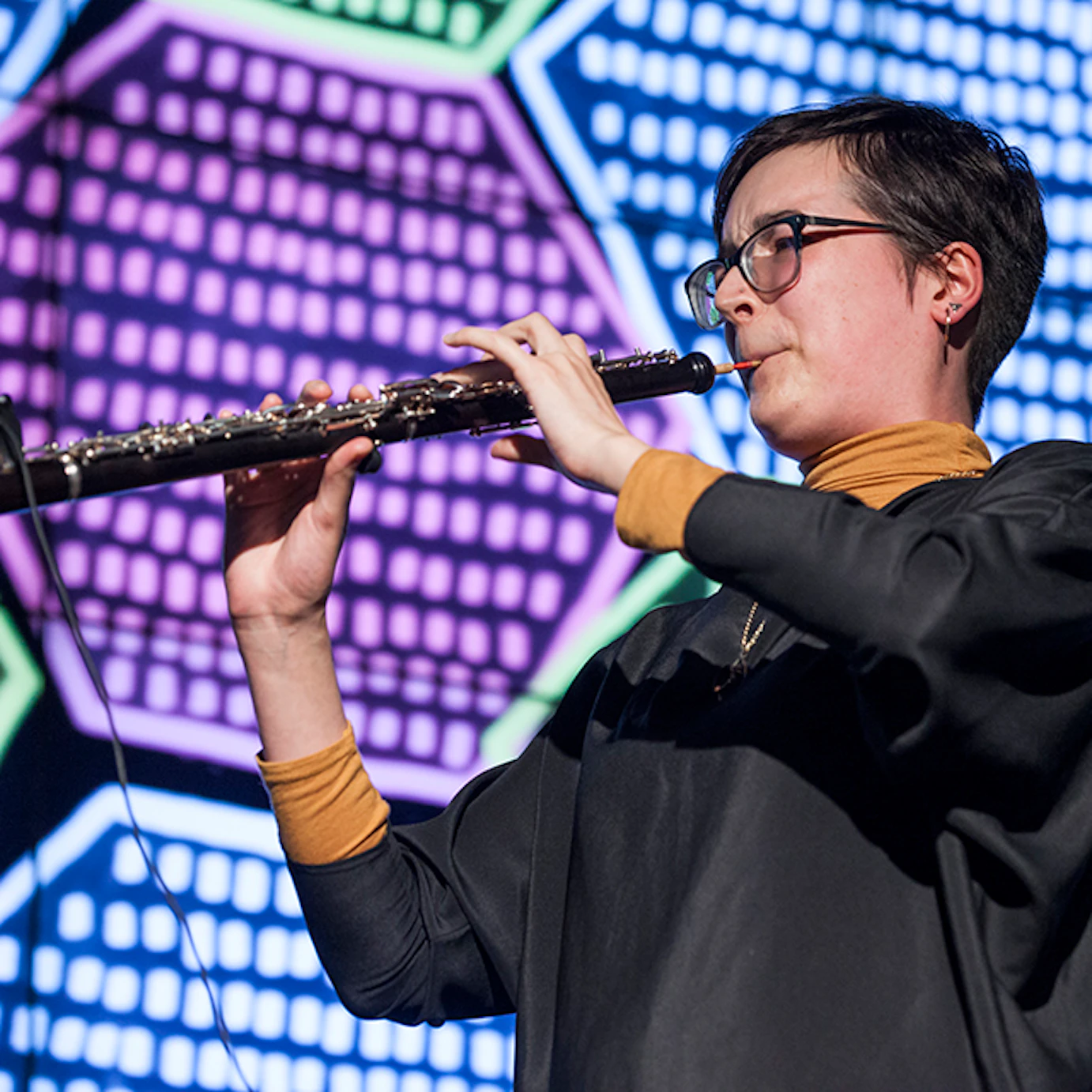 A musician playing clarinet in front of projected visuals.