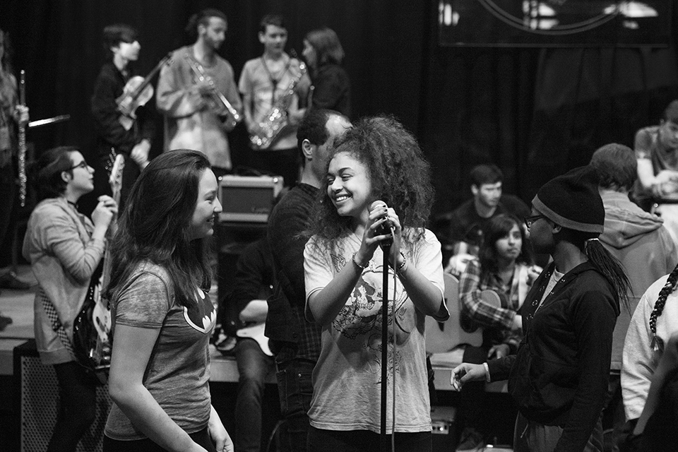 A singer surrounded by other musicians smiling.