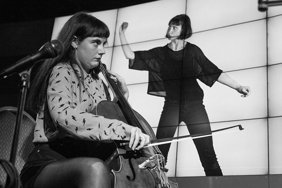 A musician playing cello in front of projected visuals.