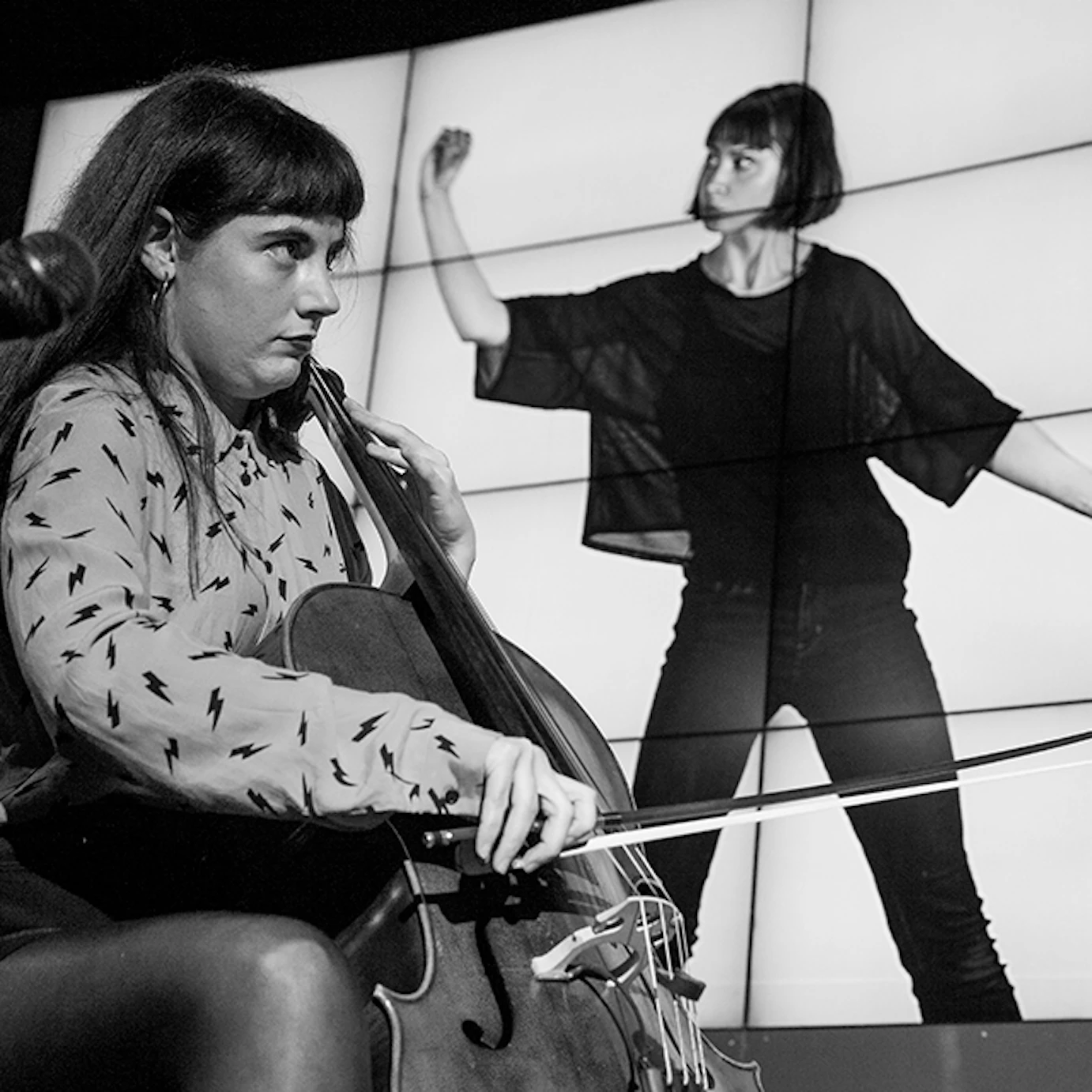 A musician playing cello in front of projected visuals.
