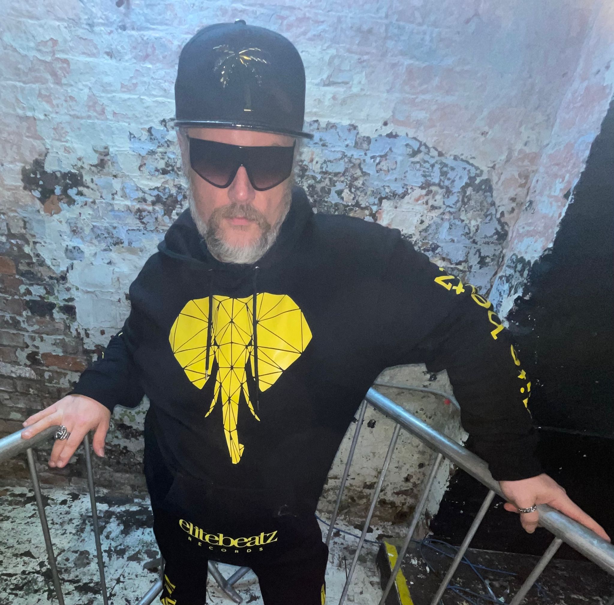 CVNT Traxxx stood in a stairwell holding two railings.