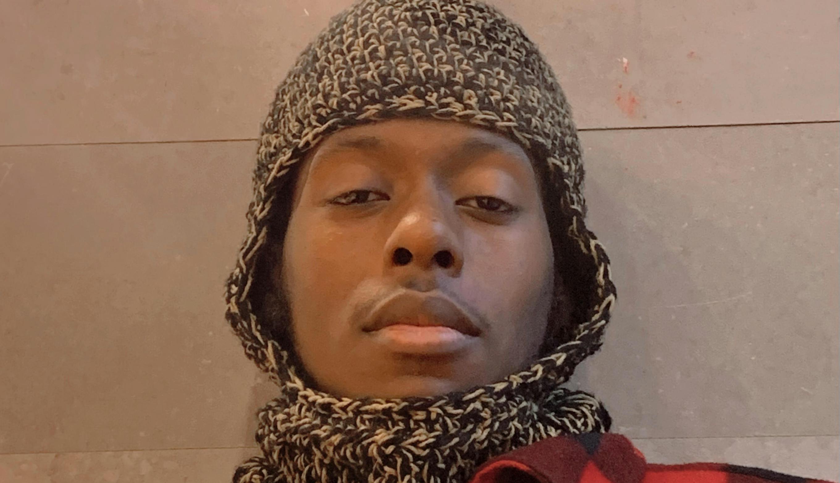 Odox looking into the camera wearing a red and black checkered jacket.