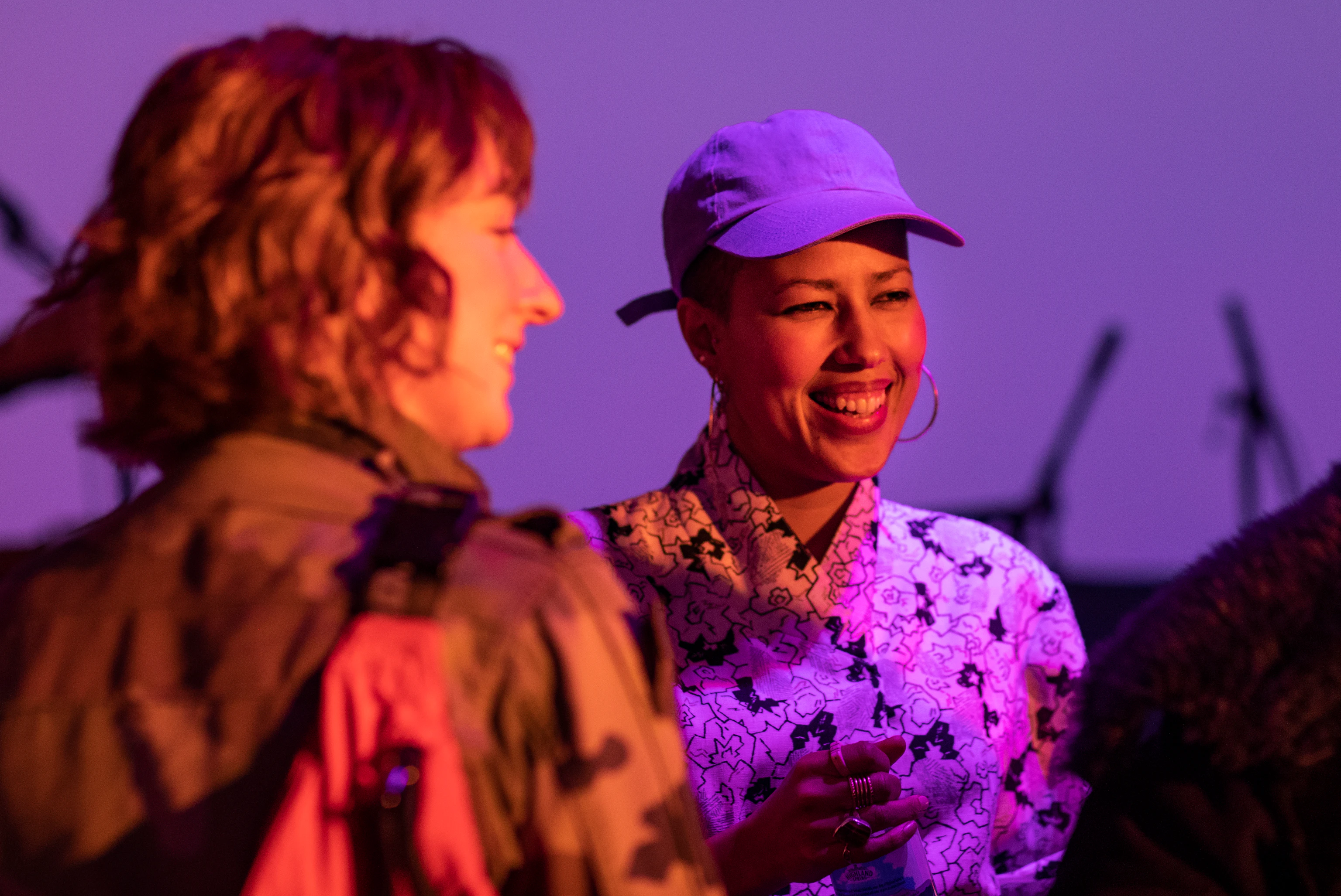 Two music professionals smiling and chatting. The room is lit with orange and purple.