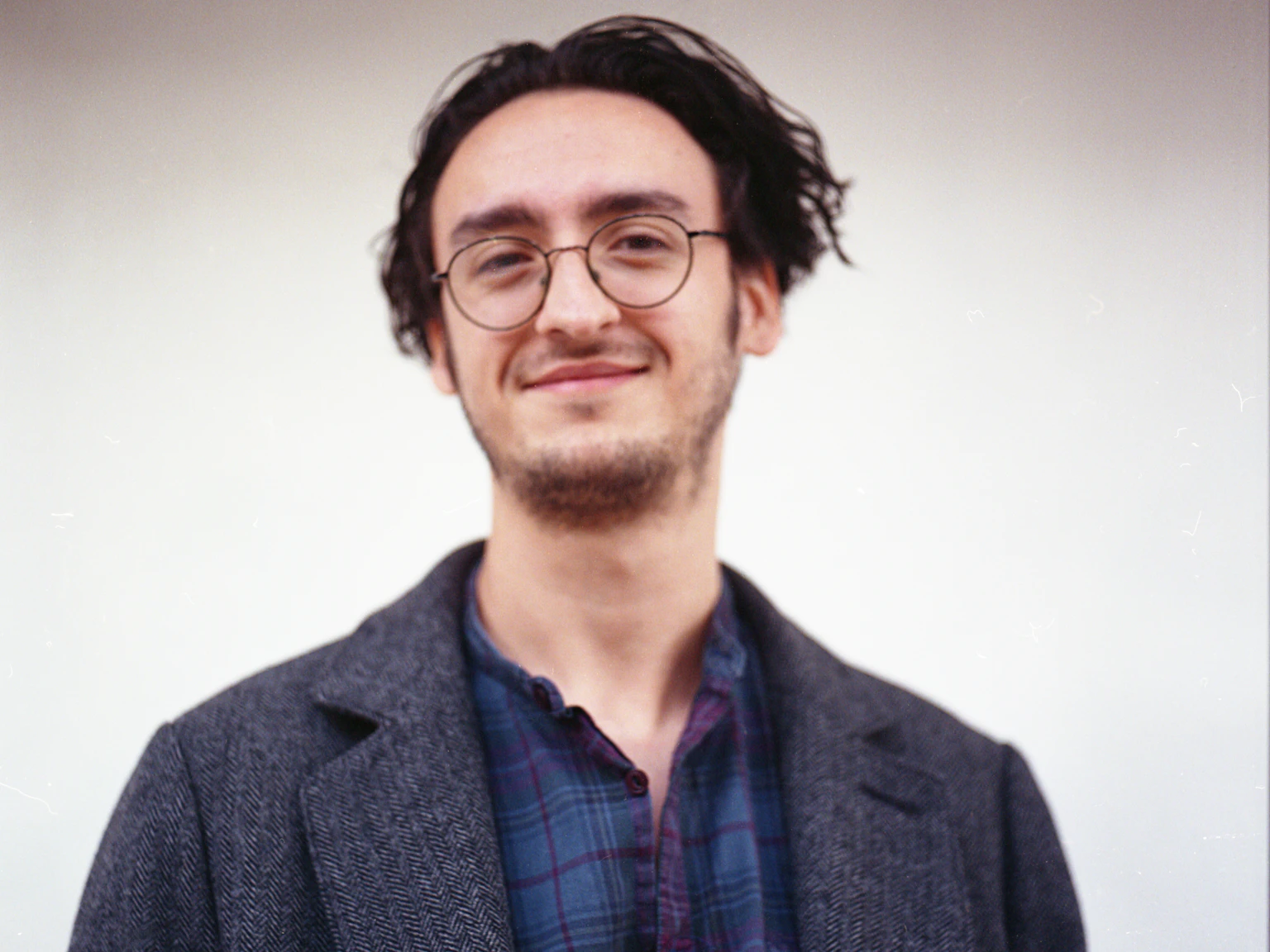 Joe smiles at the camera and is wearing a grey coat.