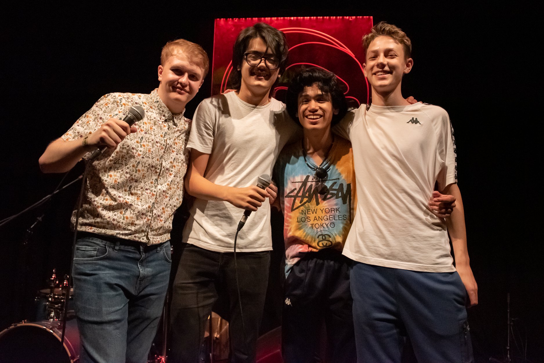 Tom and 3 other young musicians arms linked and smiling to camera.