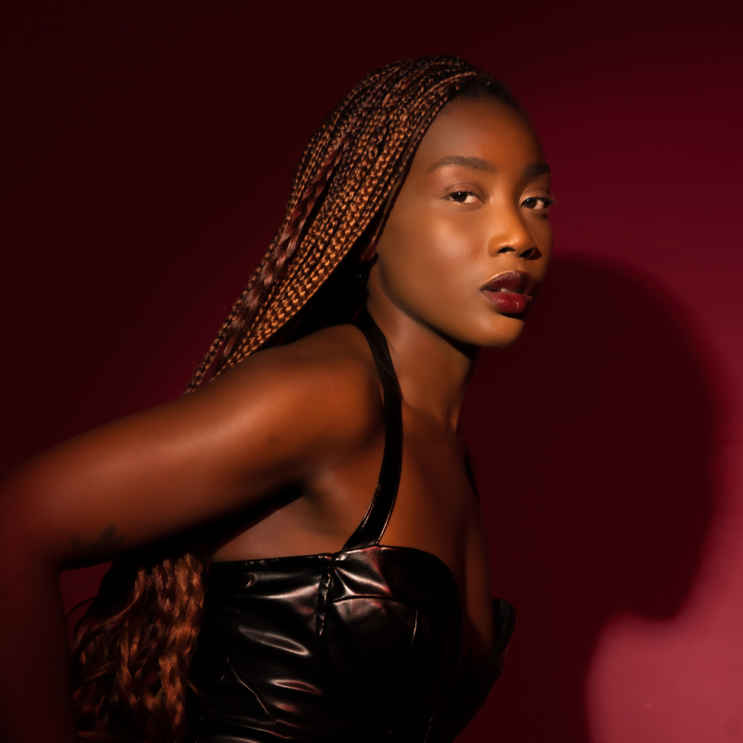 BITEZ in a black dress posing for a press shot on a red background.