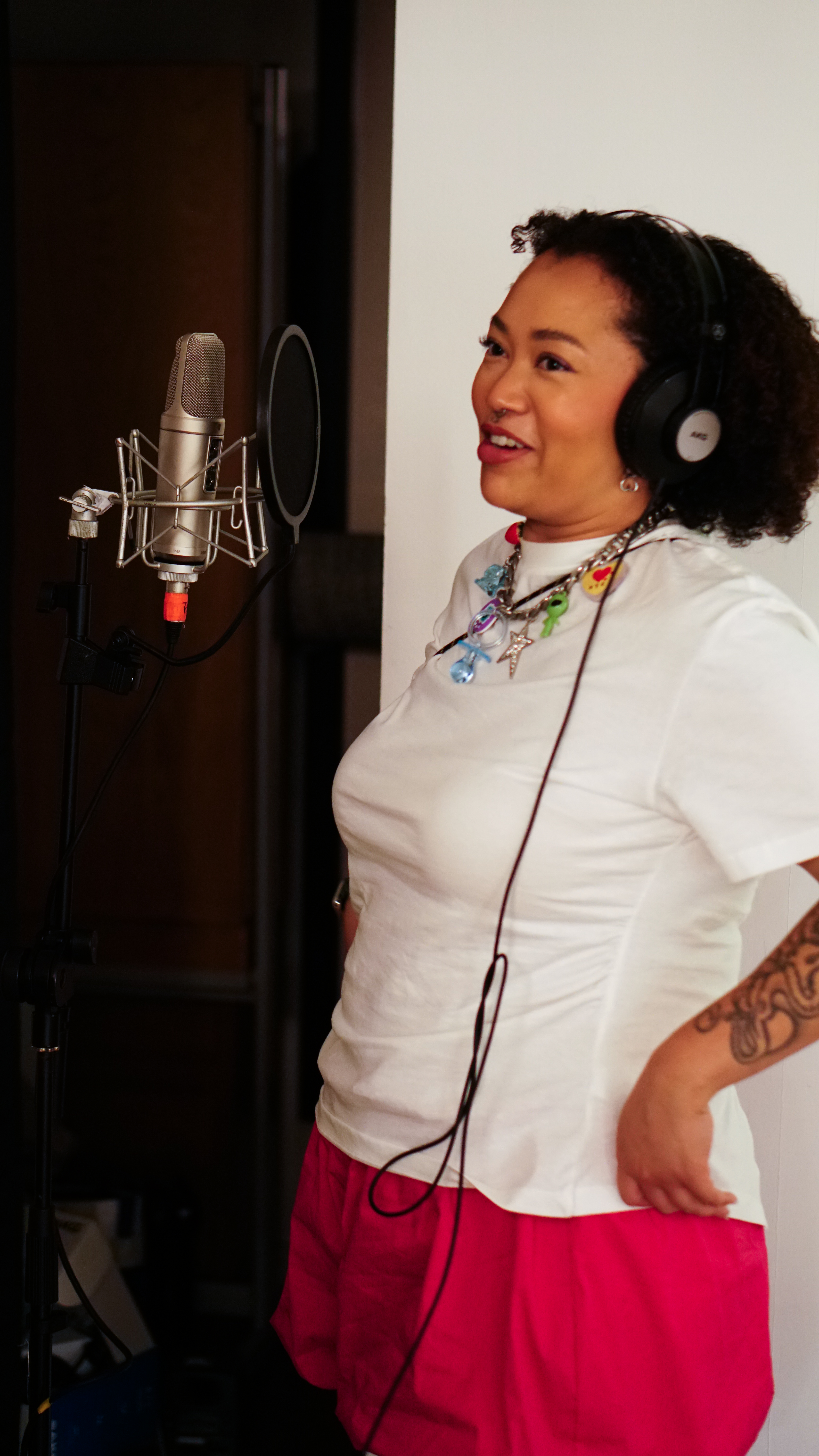 Kyami smiling with headphones on in front of a mic.