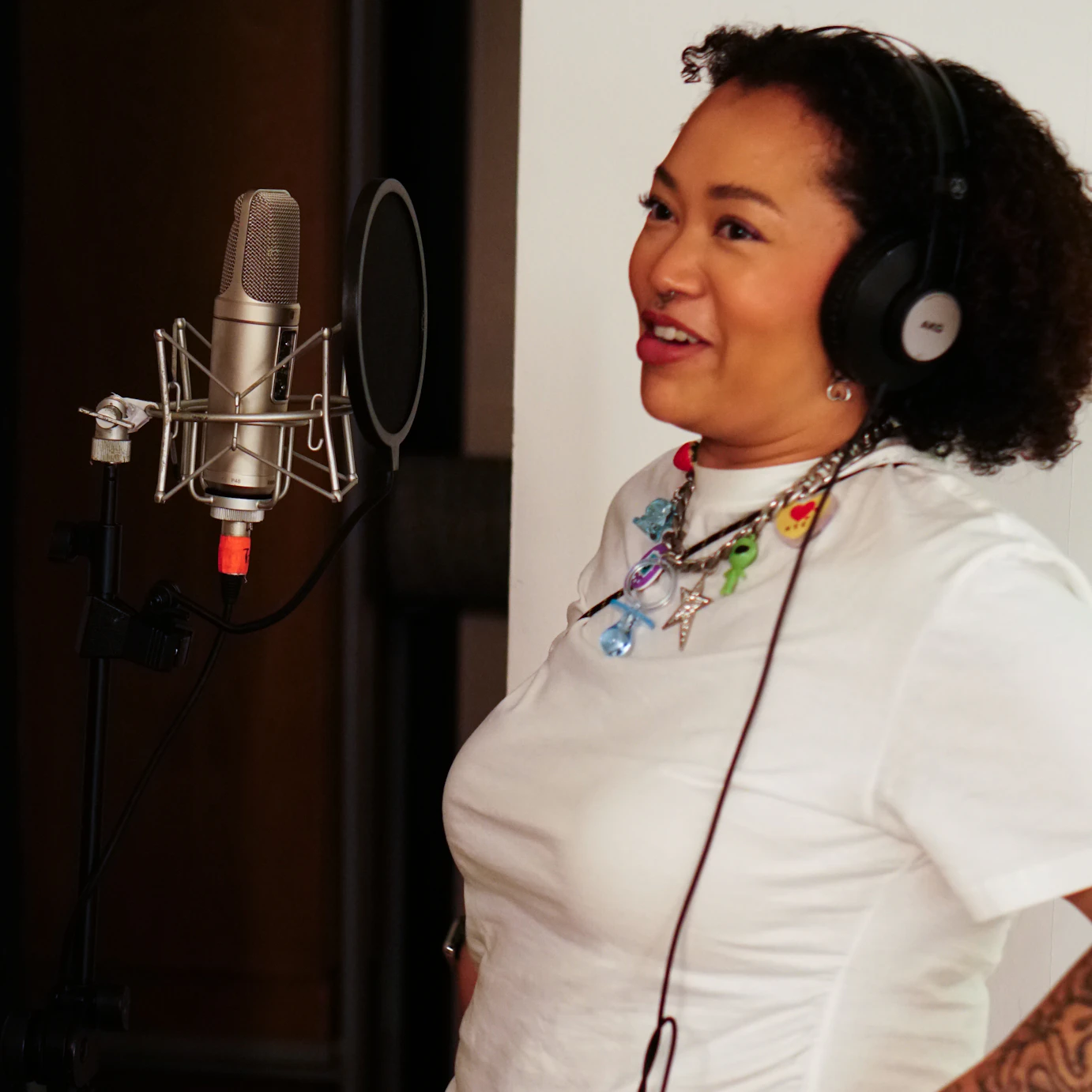 Kyami smiling with headphones on in front of a mic.
