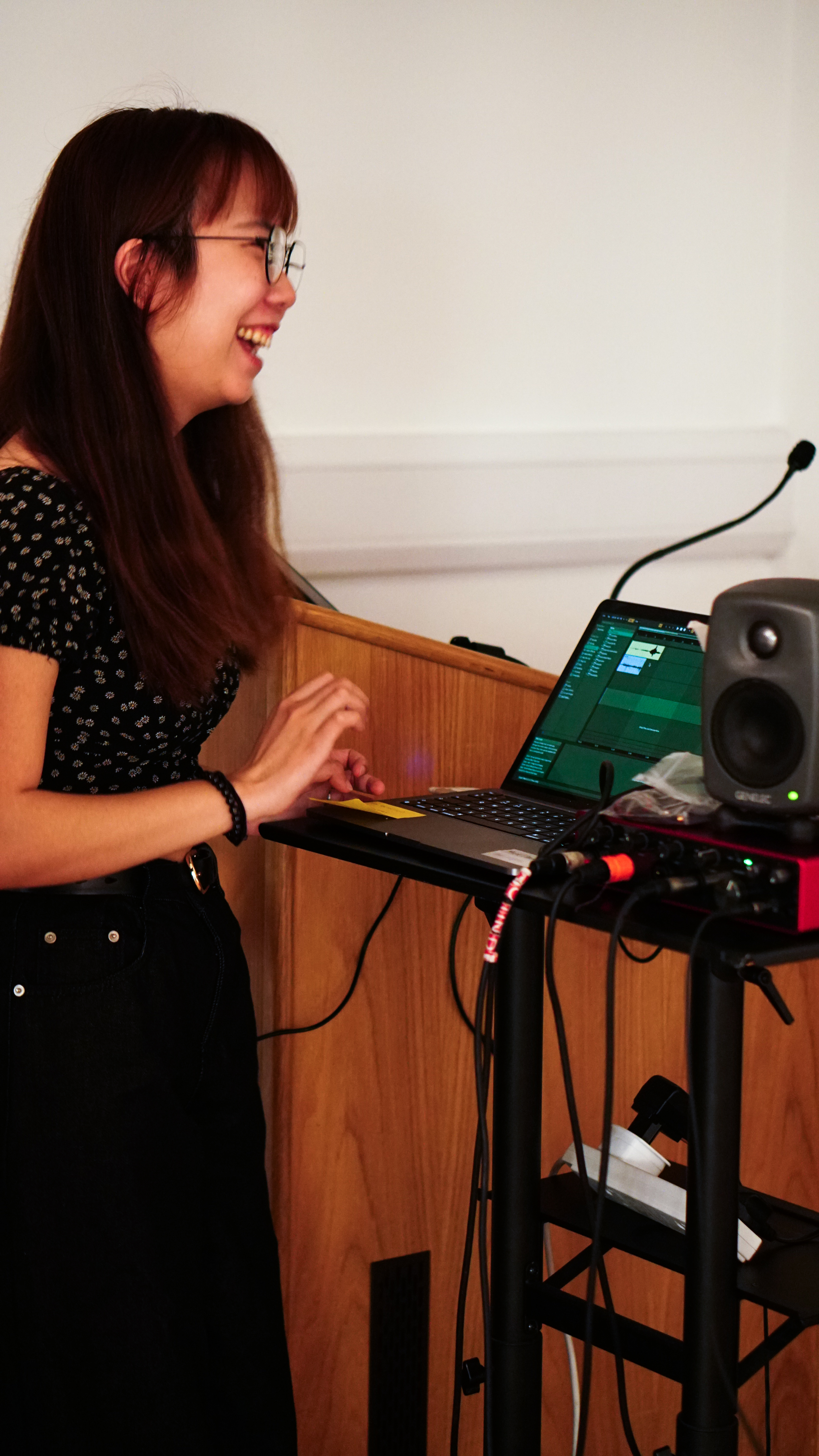 Katherine smiling in front of a laptop in rehearsals.