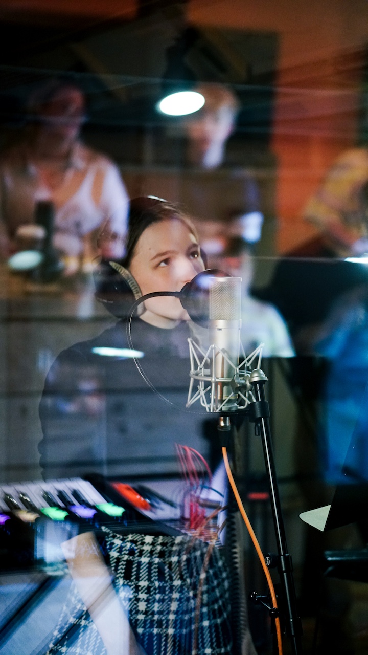 A young musician in VoltaLab with headphones on singing into a microphone.