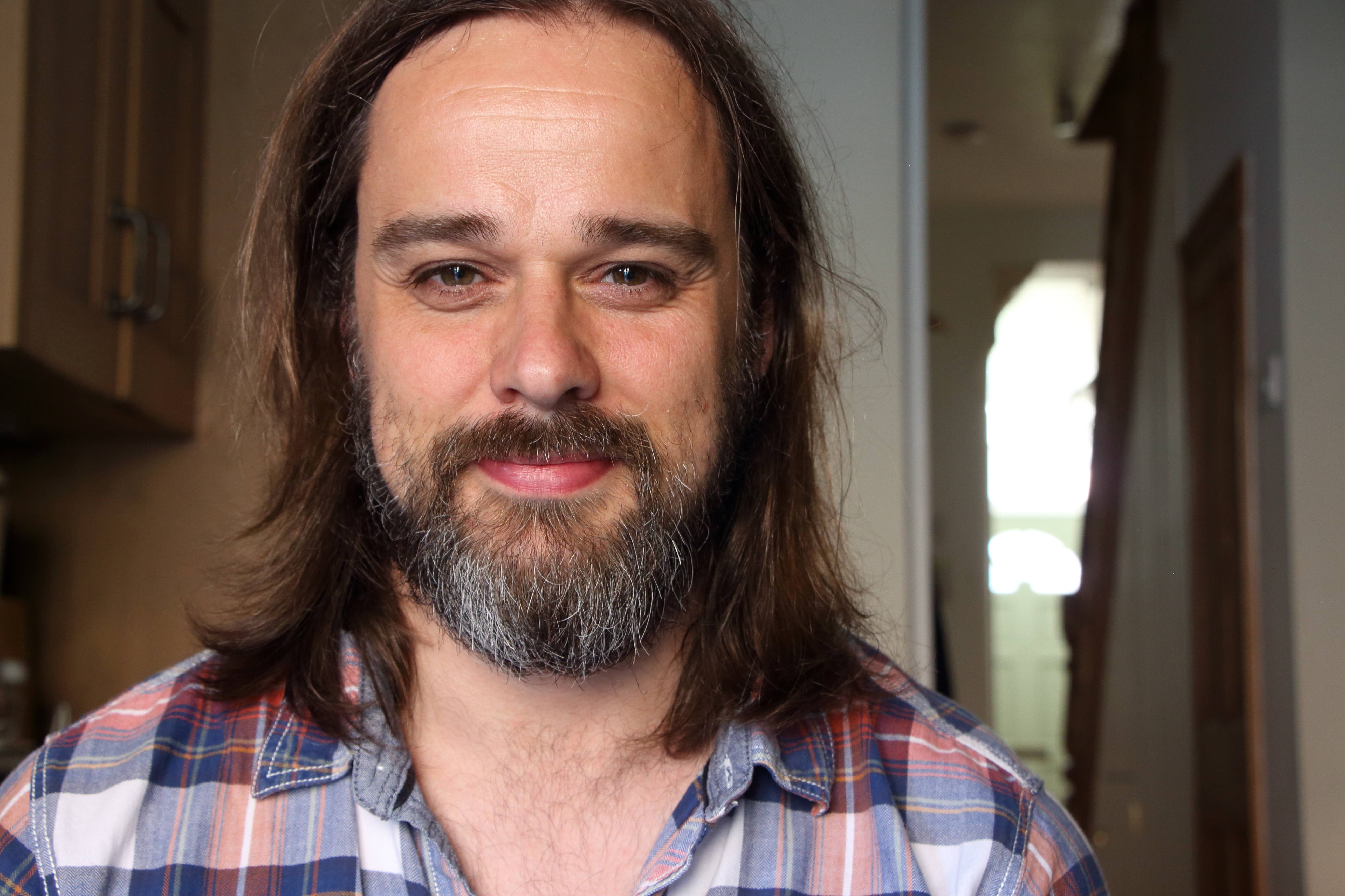 Jeff Thompson smiling to camera in a room in a domestic house.