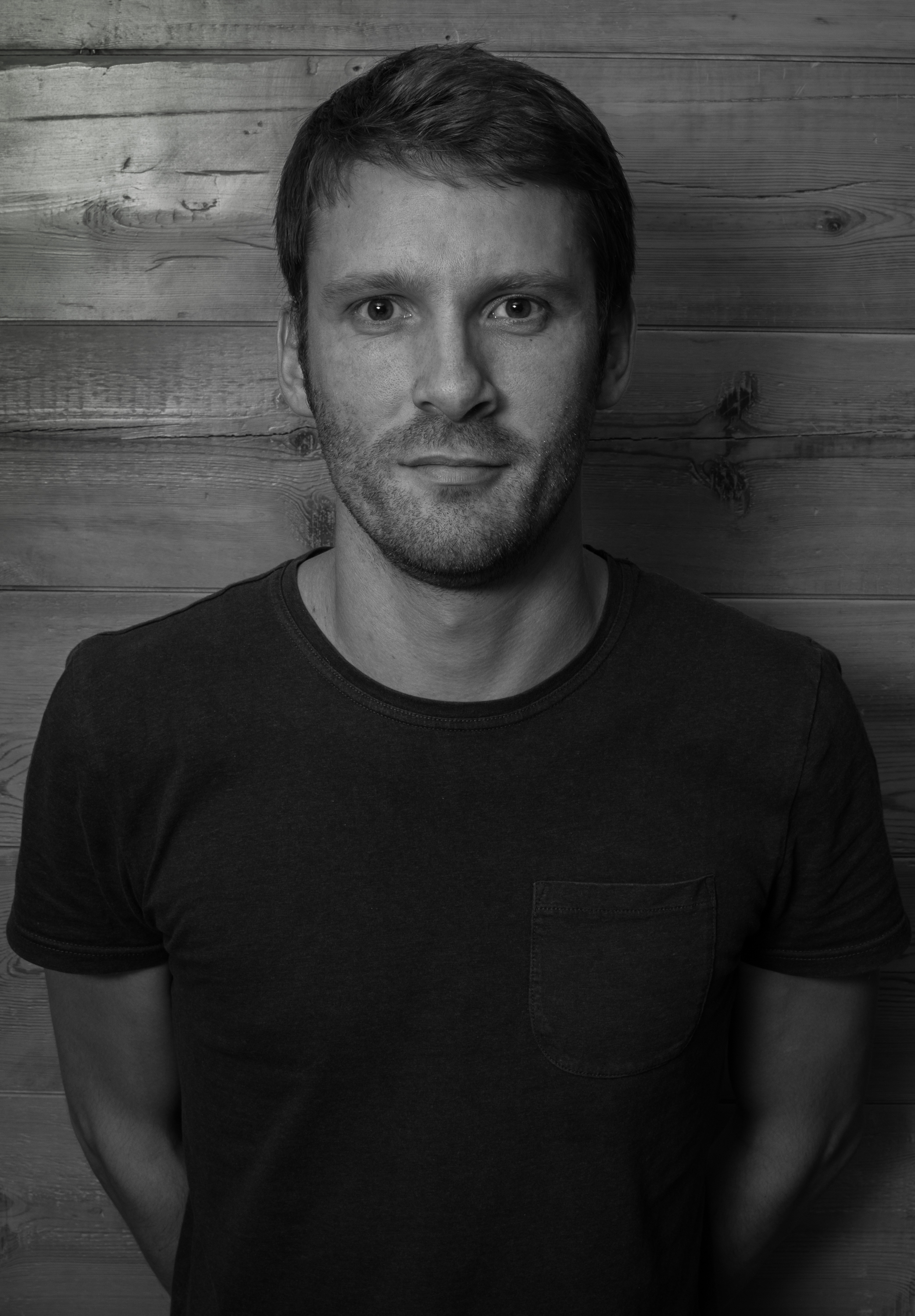 Sam Potts looking to camera against a wooden wall.