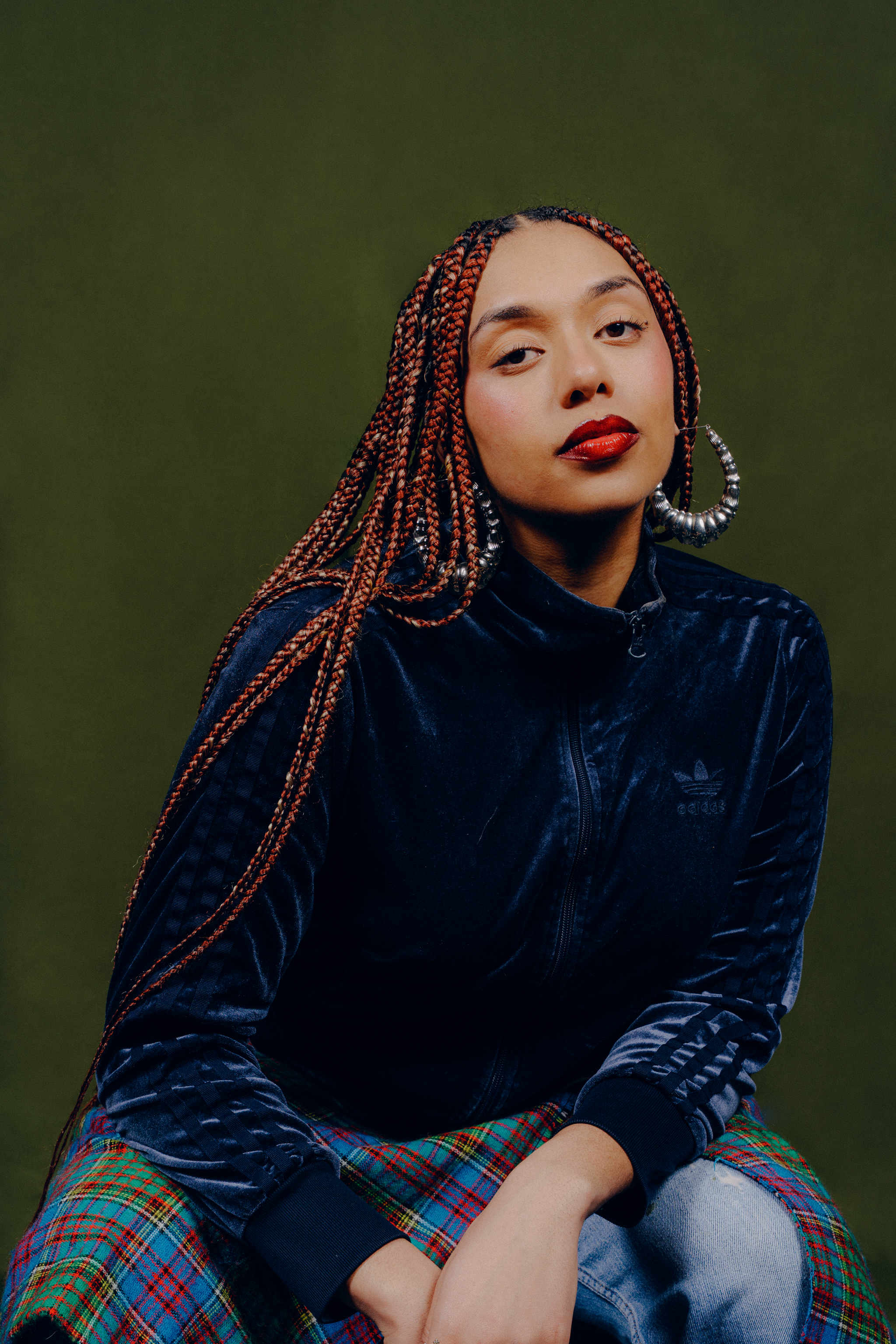 Yelena Lashimba looking to camera sat against a dark green backdrop.