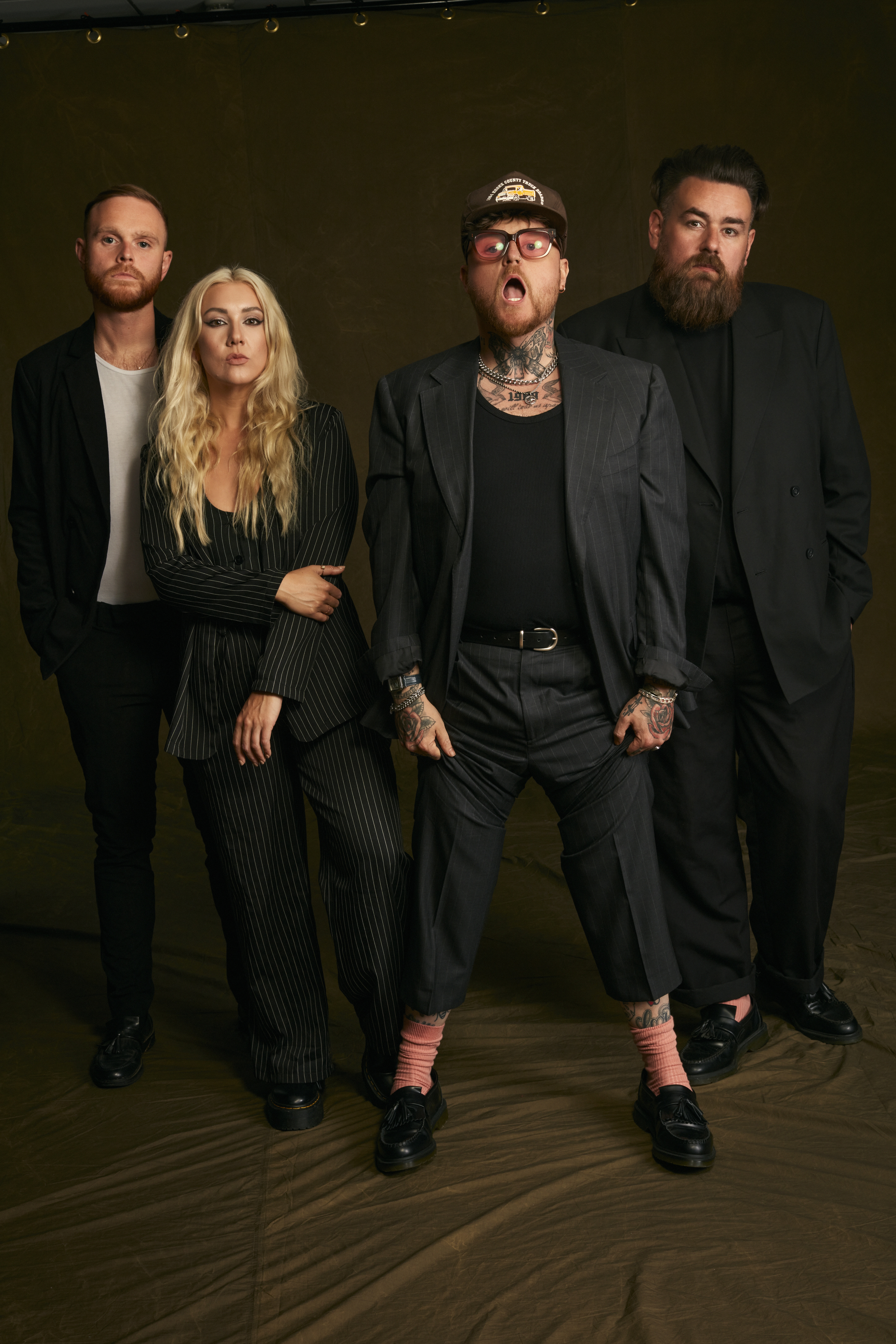 The Lottery Winners in dark suits posing in a studio.