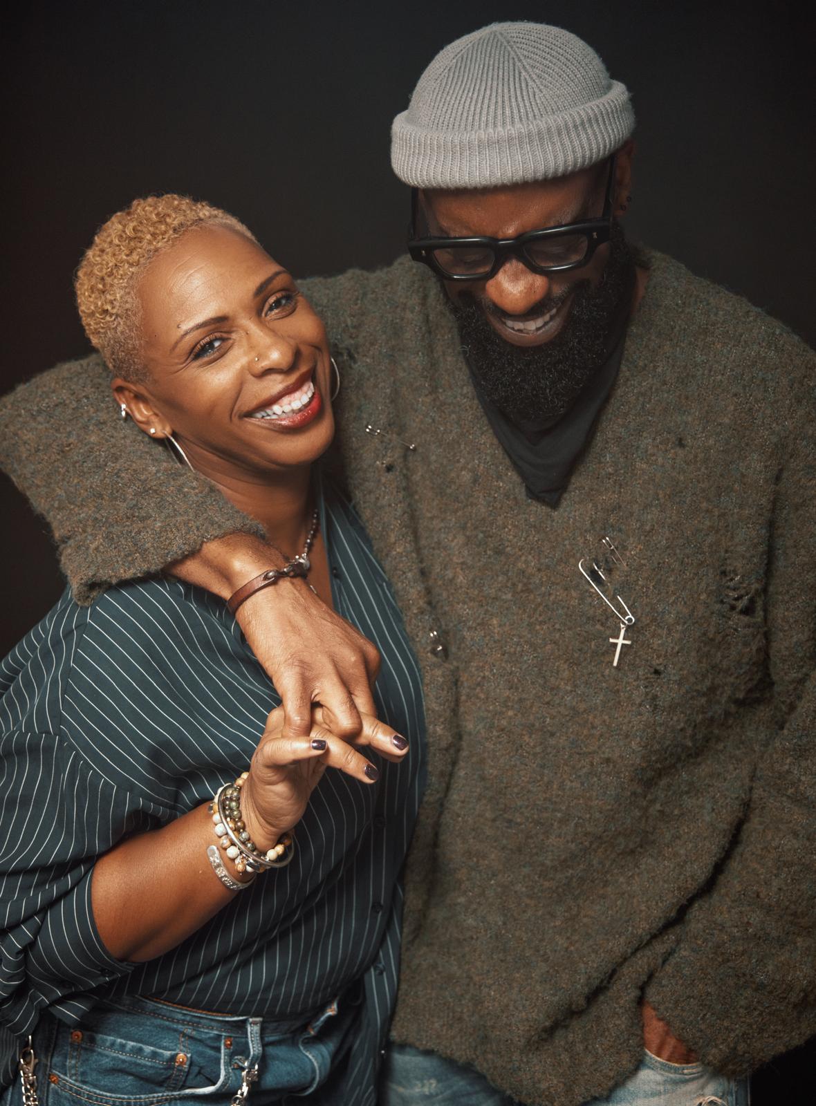 Michelle Escoffery and Osiki Ojo smiling and laughing. Osiki has an arm around Michelle and their hands are linked.