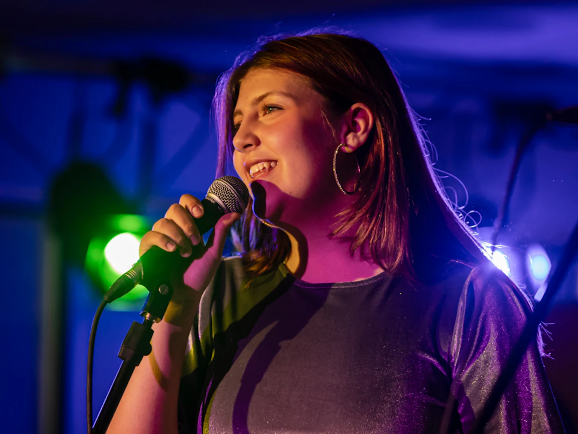 Young musician smiling with a microphone.