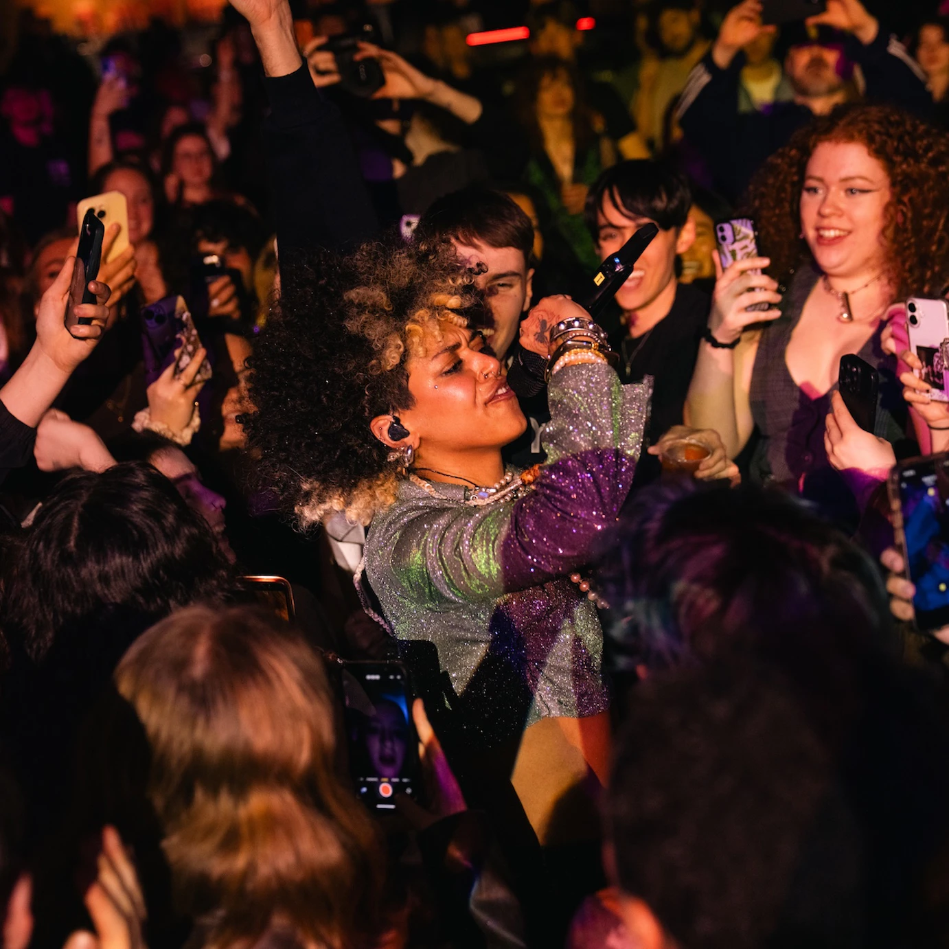 Nxdia signing into a mic surrounded by fans.