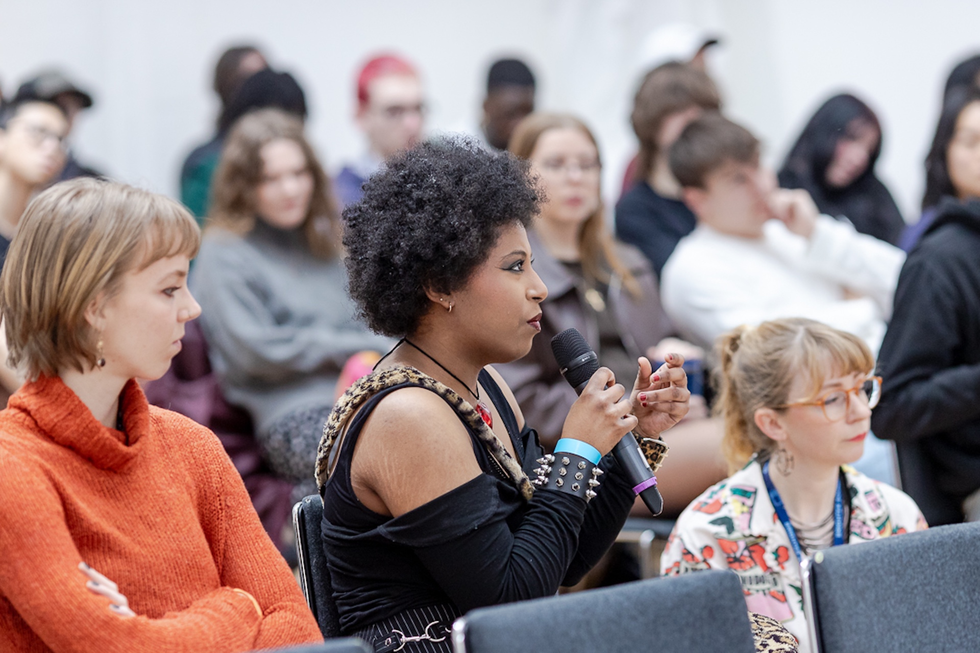 A young musician in a crowd speaking into a microphone during a panel event.