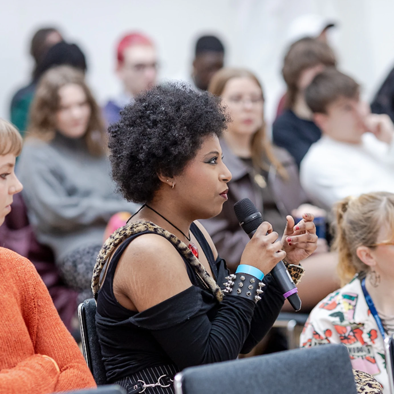 A young musician in a crowd speaking into a microphone during a panel event.
